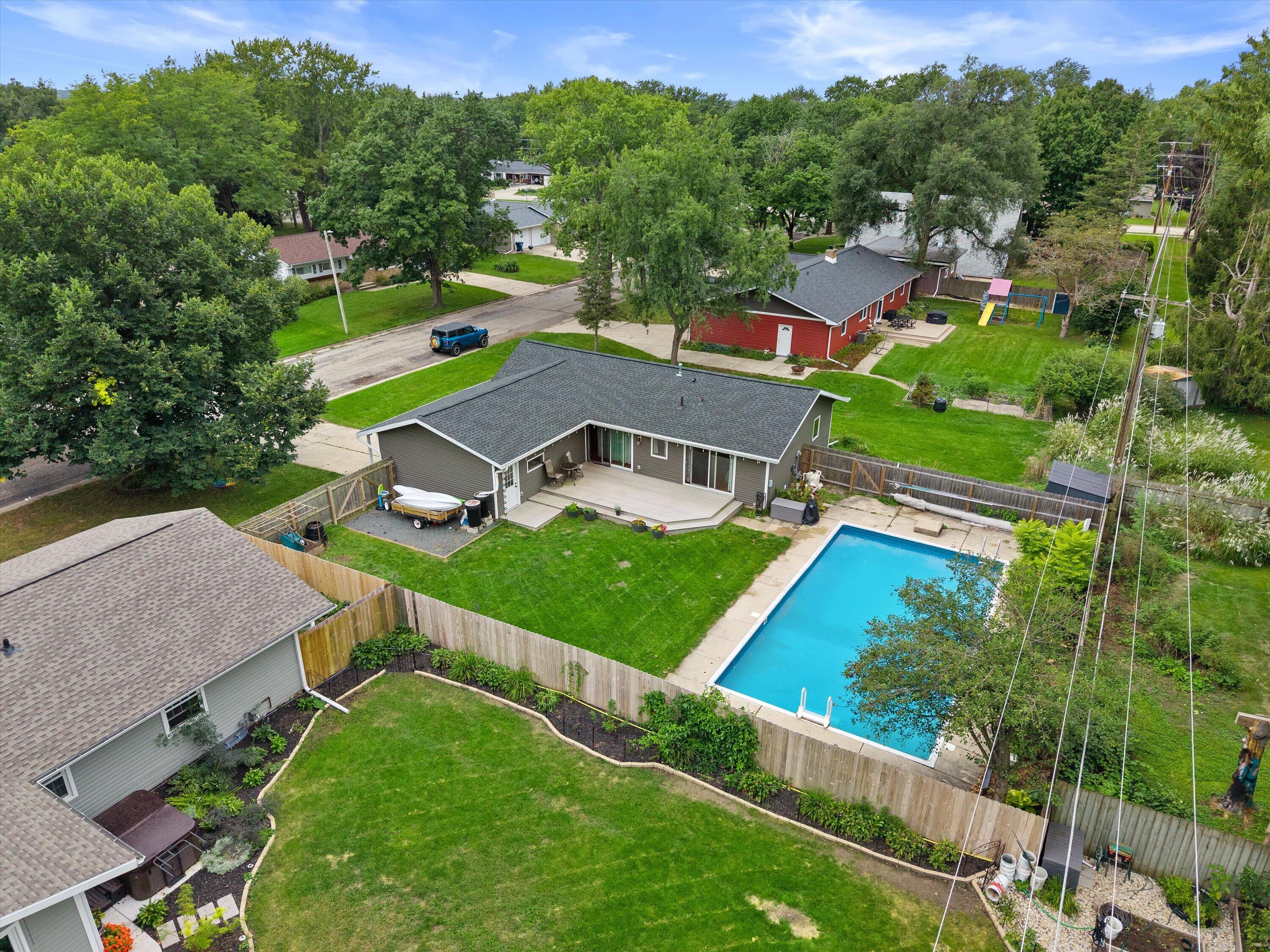 Aerial view of a home with a fenced backyard, swimming pool, and patio deck.