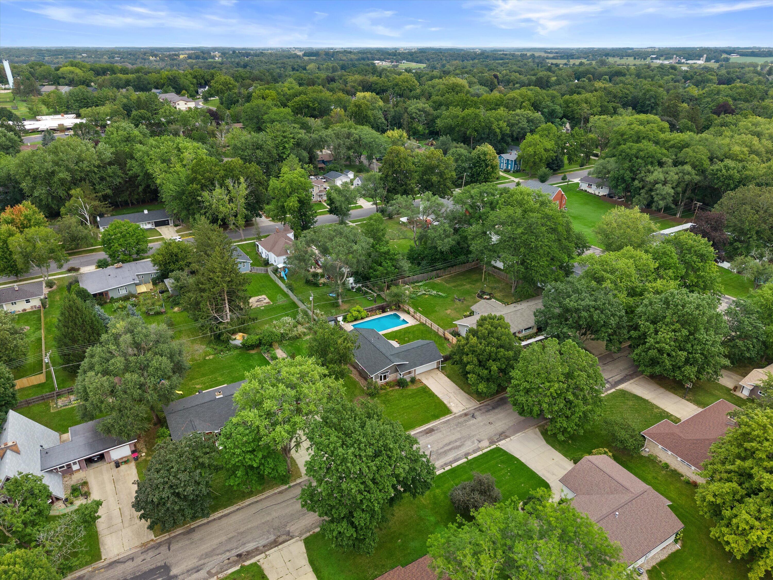 Aerial view of a tree-lined residential neighborhood, with a backyard pool and homes along quiet streets.