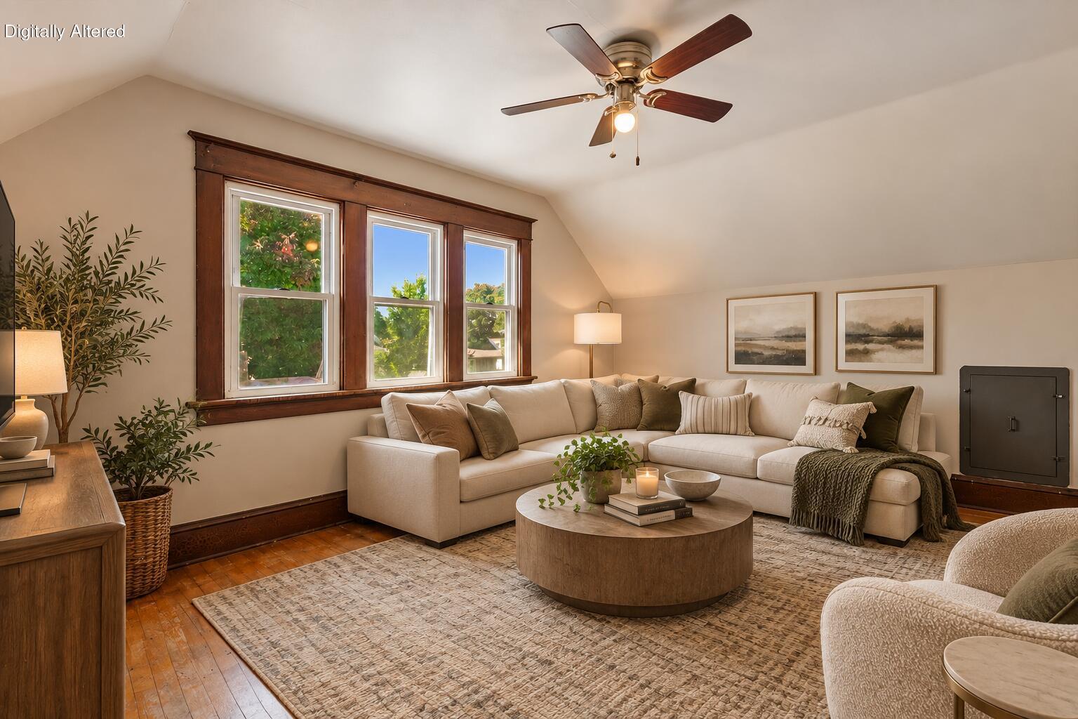 Staged living room with a cream sectional, tall wood-trimmed windows, and a ceiling fan.