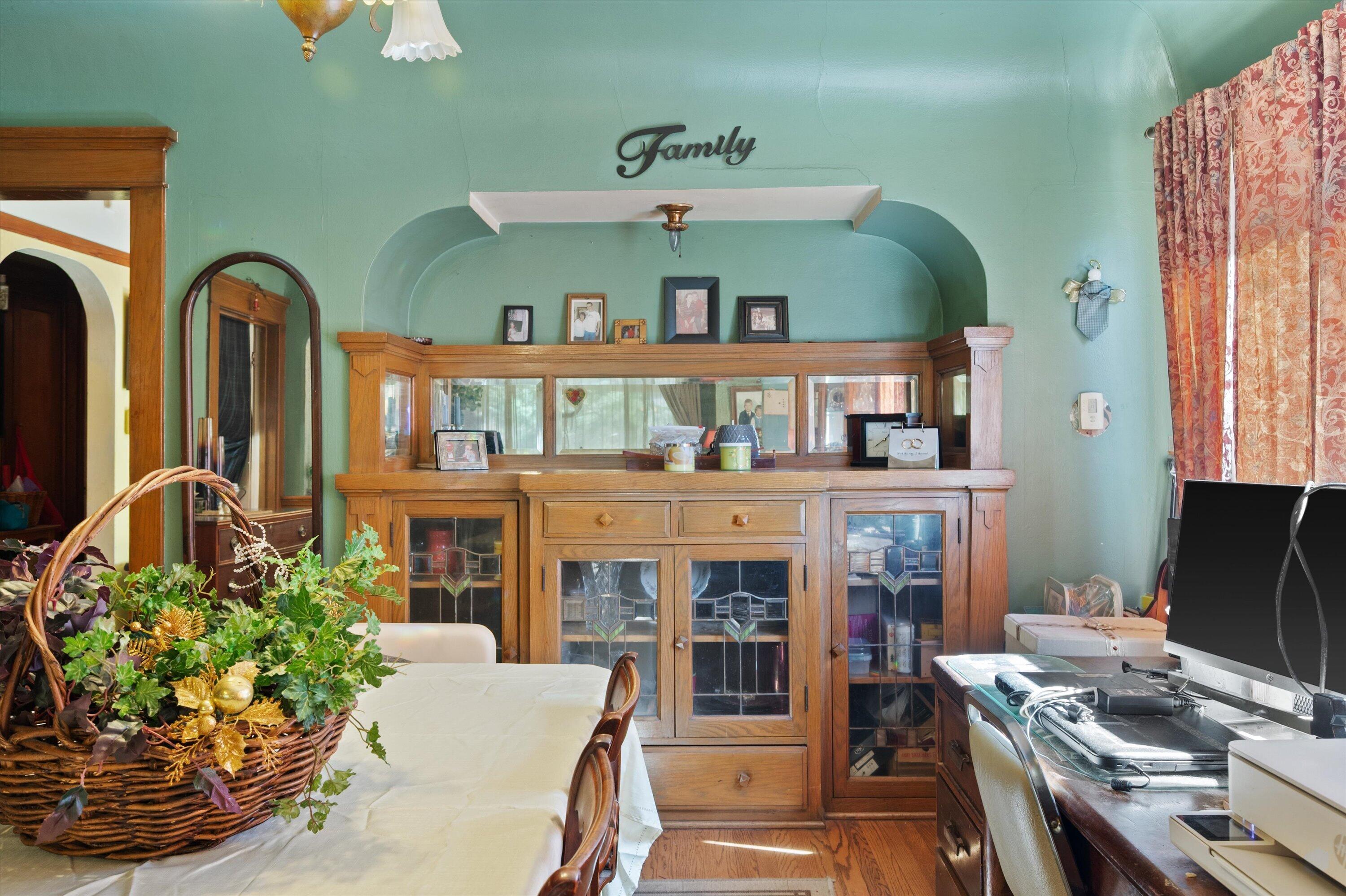 Dining room with a large wooden china cabinet, mint-green walls, and a basket centerpiece on the table.