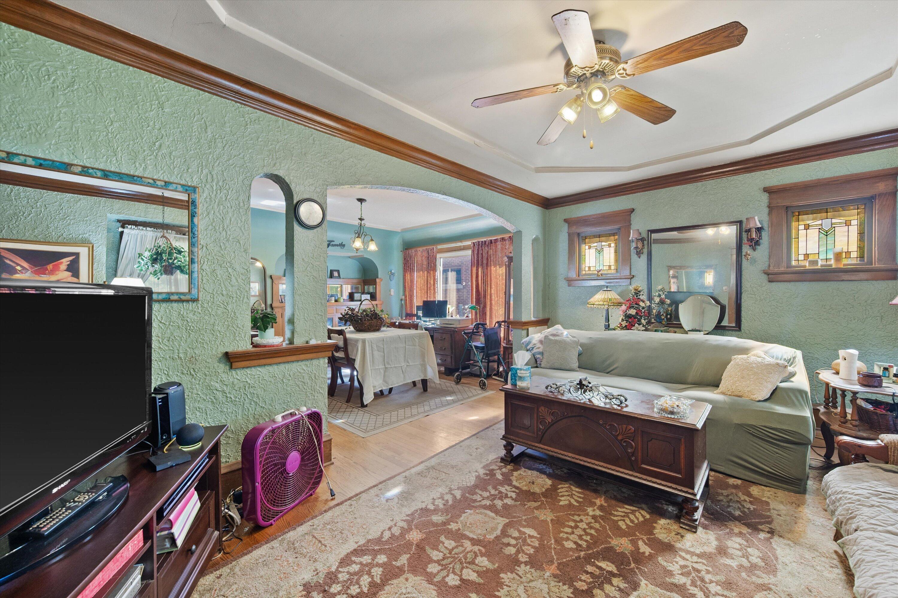Living room with green textured walls, stained-glass windows, and an arched opening to the dining area.