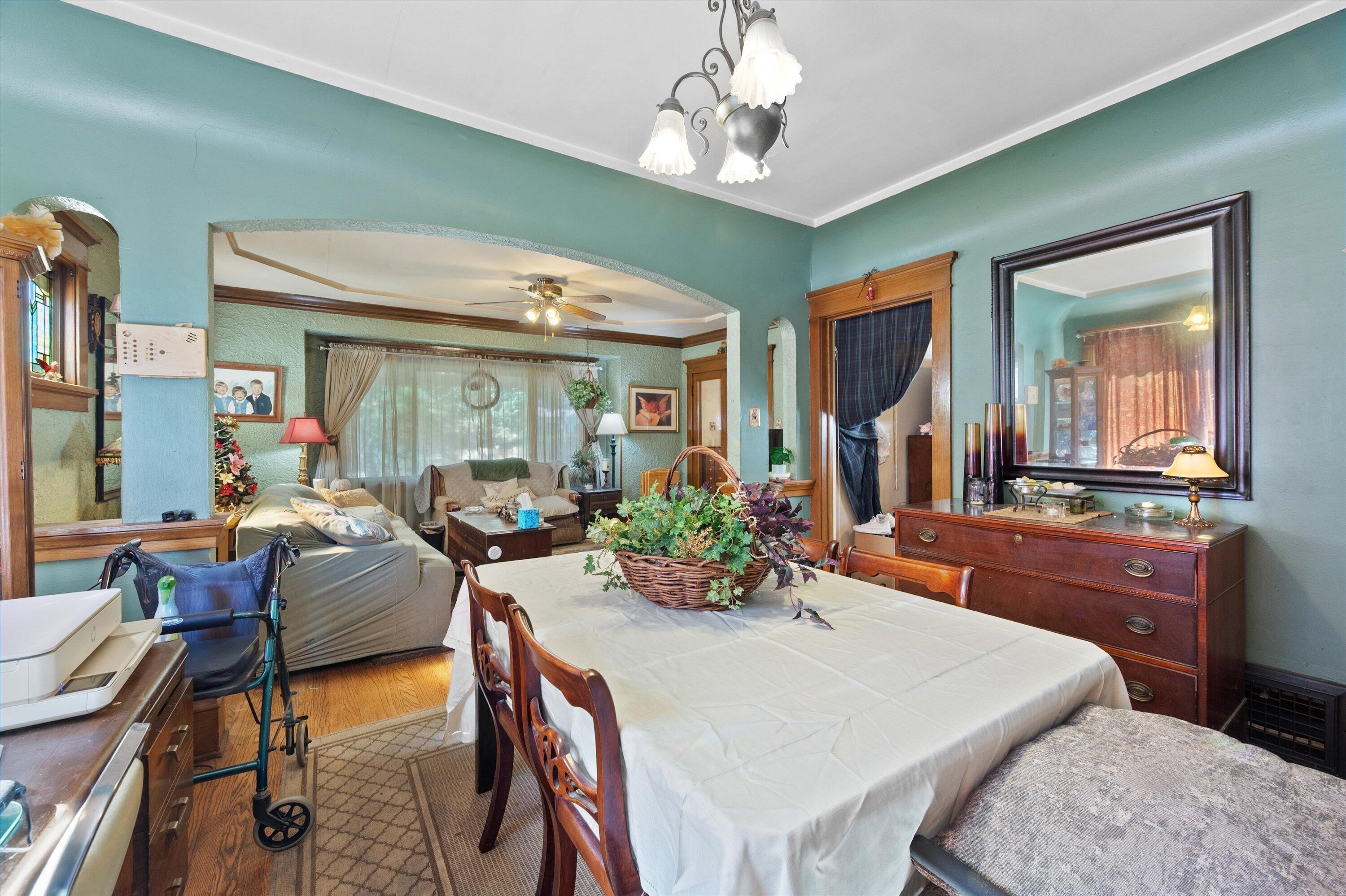 Furnished dining room with turquoise walls, a flower centerpiece, and an arched opening to the living room.