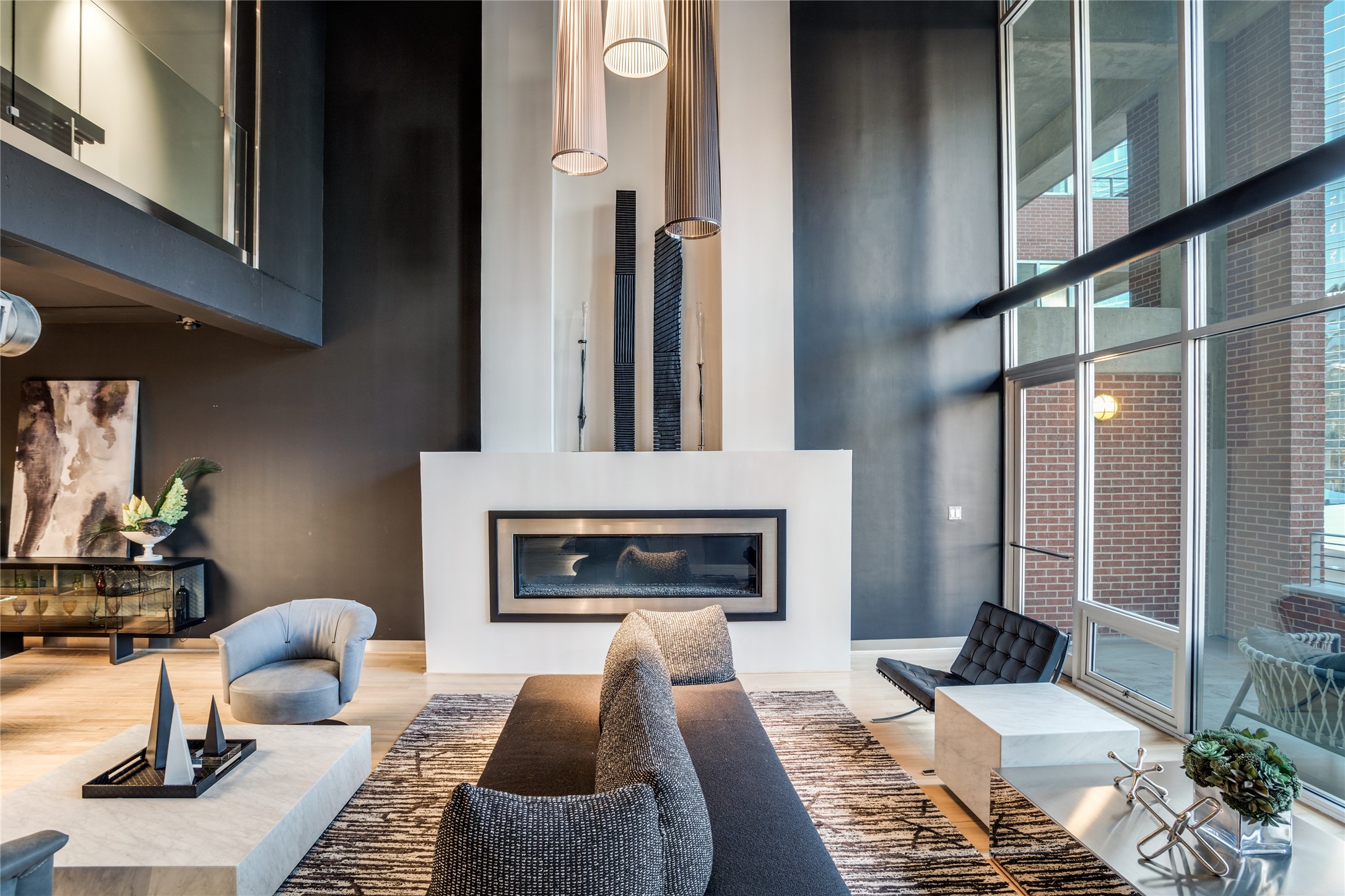 Modern condo living room with a linear fireplace, double-height windows, and contemporary furnishings.