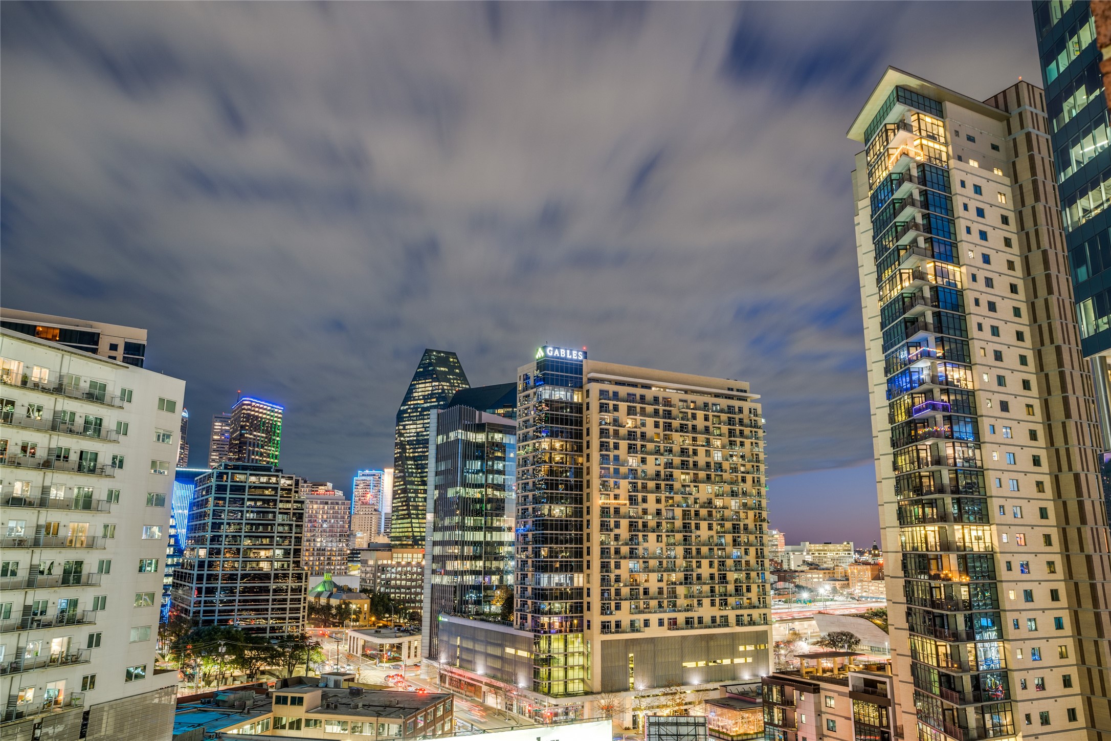 Downtown Dallas skyline at night, with illuminated high-rises and the Gables building.