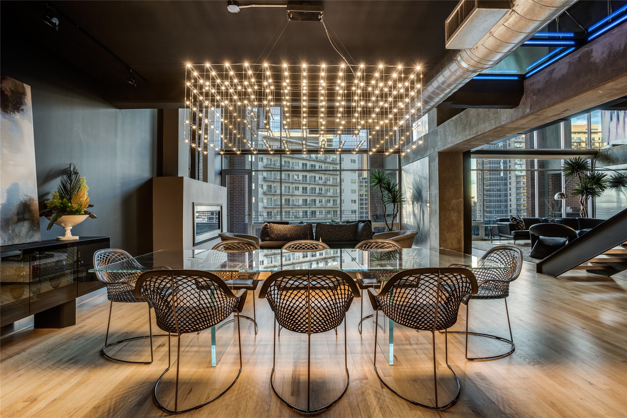 Contemporary condo dining area with a glass table, sculptural chandelier, and city views.