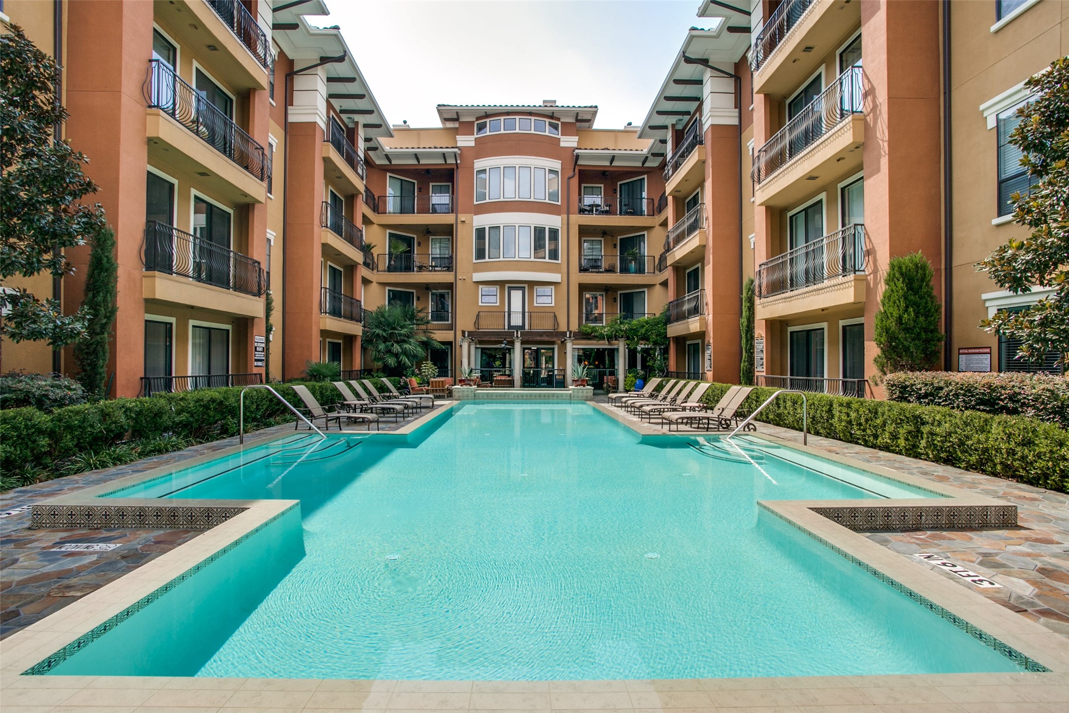 Courtyard pool surrounded by condominium balconies and lounge chairs.