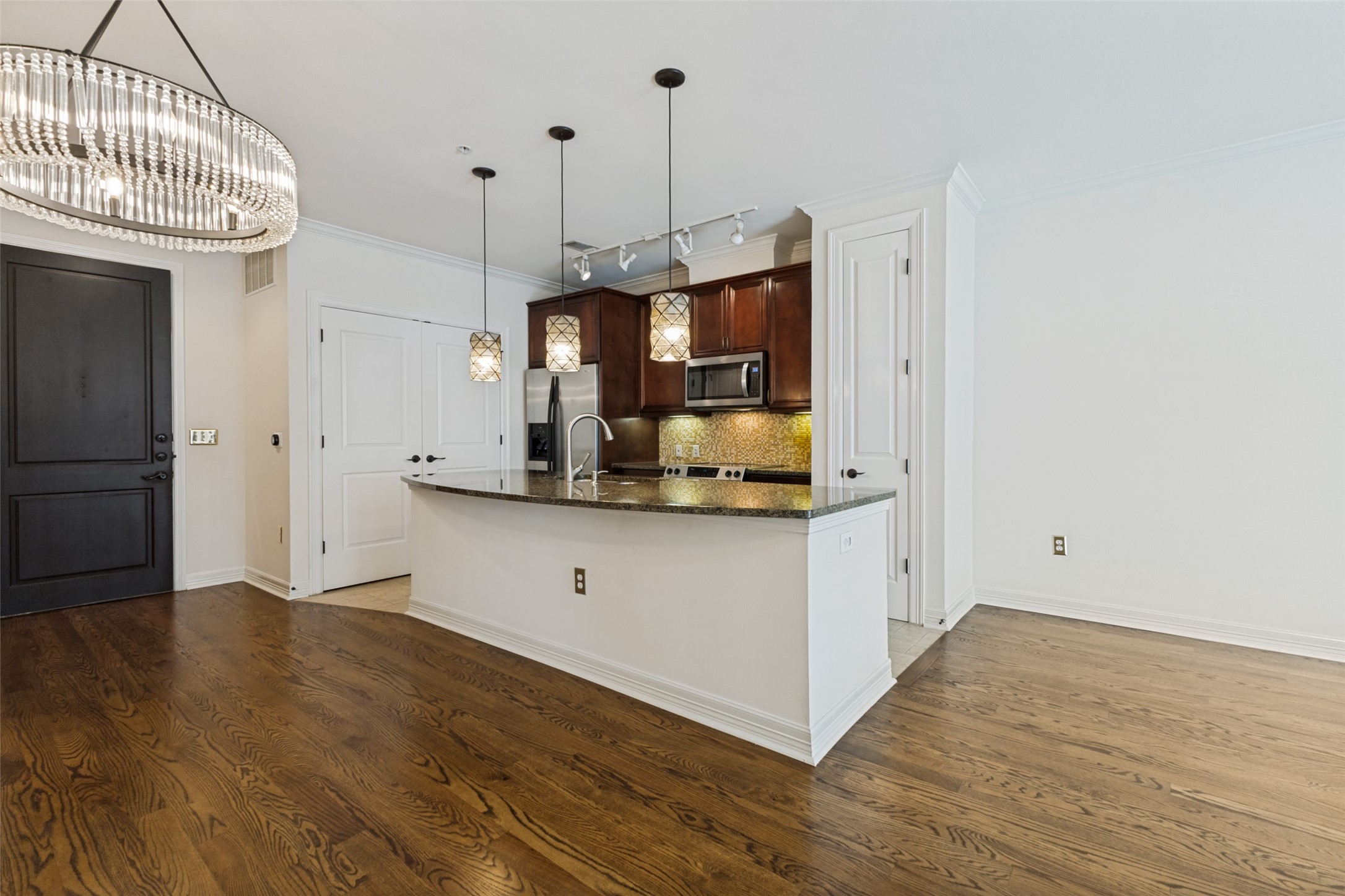 Kitchen with a granite island, dark wood cabinetry, stainless steel appliances, and hardwood floors.