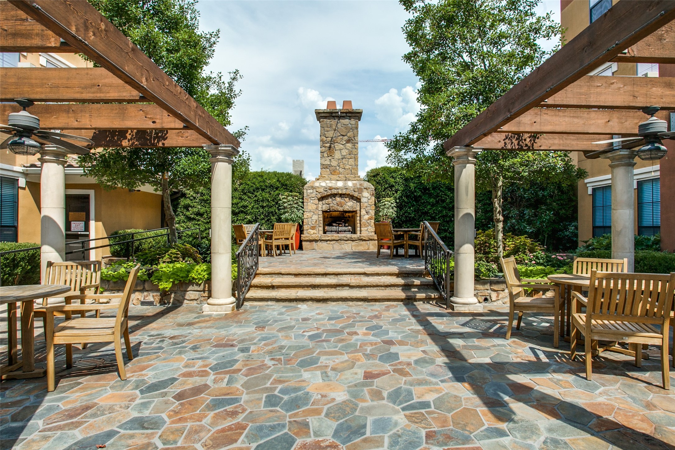 Outdoor patio with wooden pergolas, stone fireplace, and seating.
