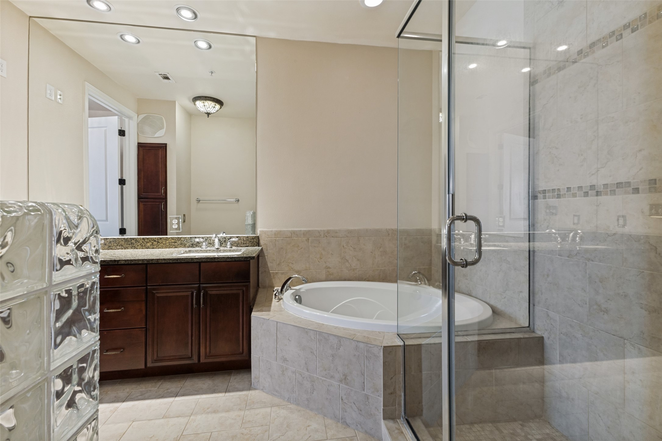 Bathroom with dark wood vanity, tiled soaking tub, and glass-enclosed shower.