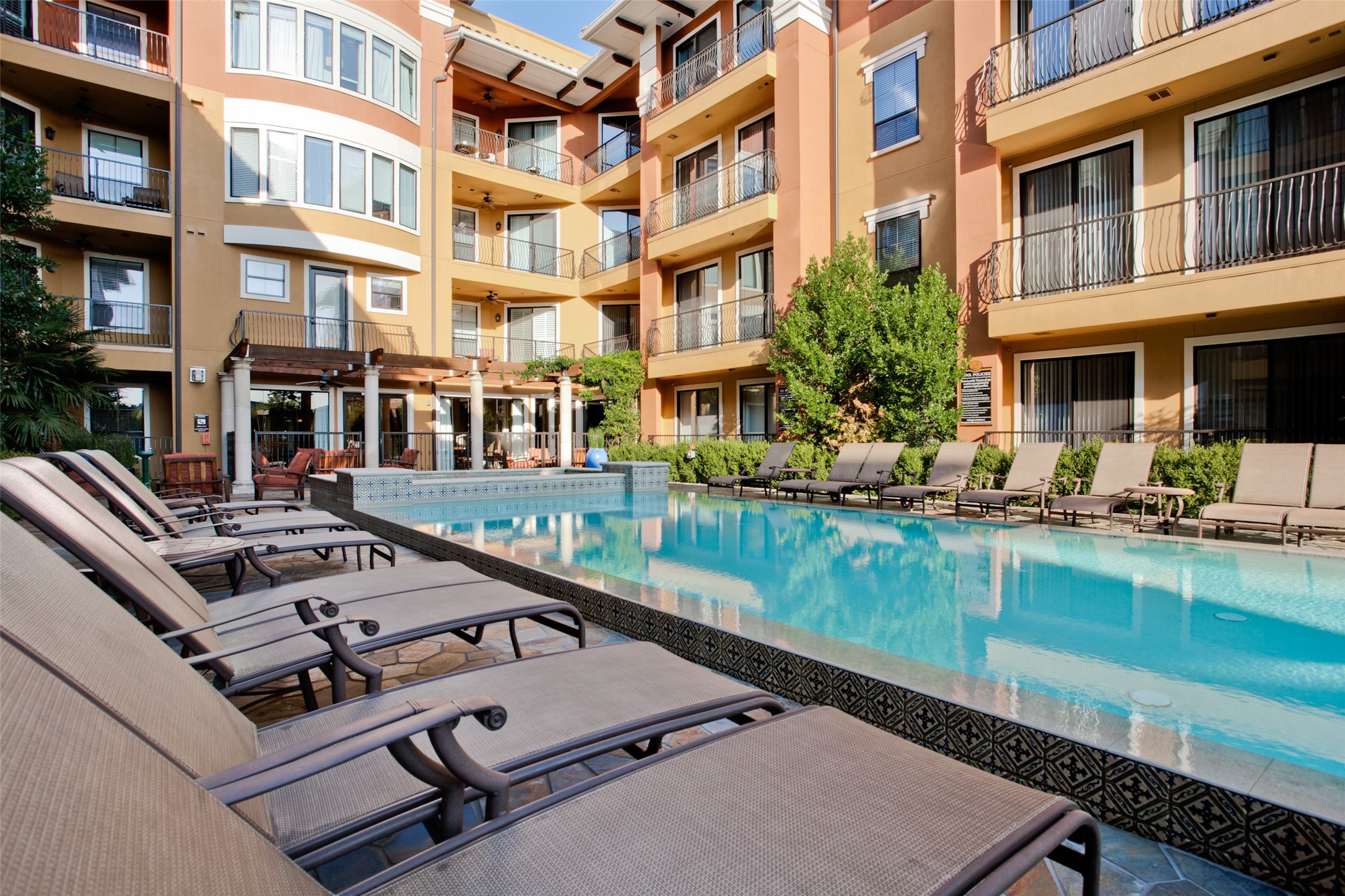 Apartment courtyard pool with patterned tile, lounge chairs, and surrounding balconies.