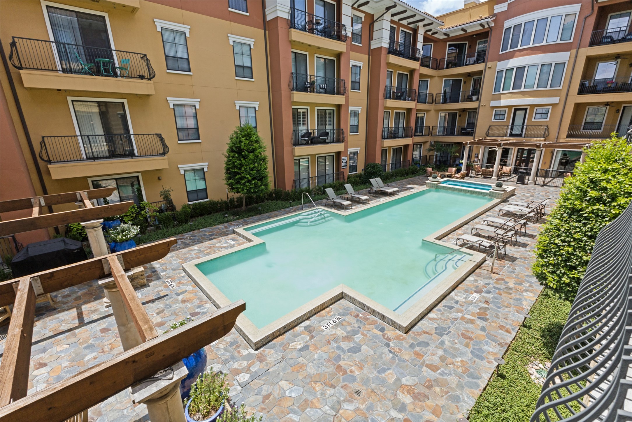 Courtyard swimming pool with tiled deck, lounge chairs, and surrounding apartment balconies.