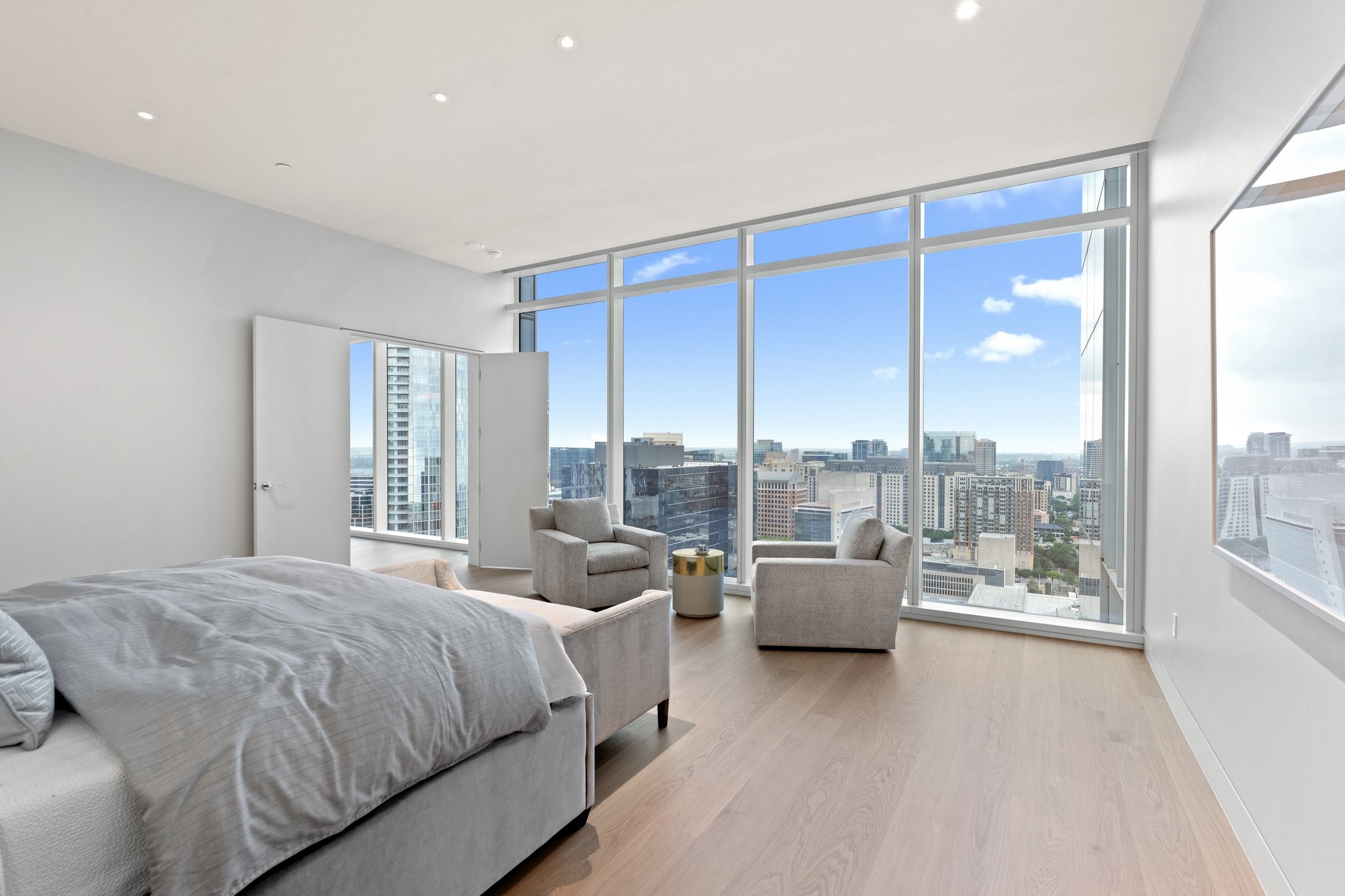 High-rise bedroom with floor-to-ceiling windows overlooking downtown Dallas.