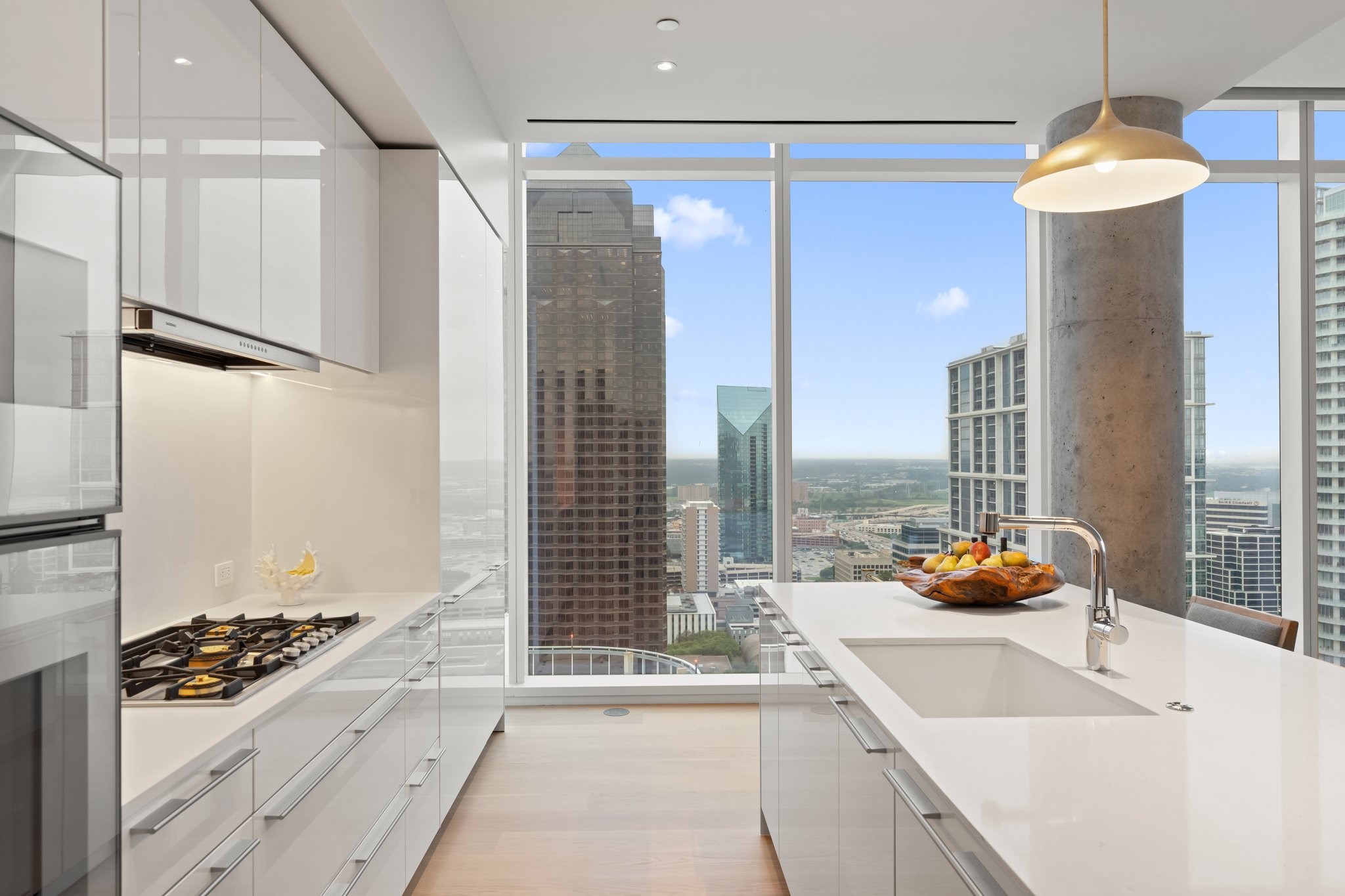 Modern white kitchen with a large island and floor-to-ceiling windows overlooking the downtown skyline.