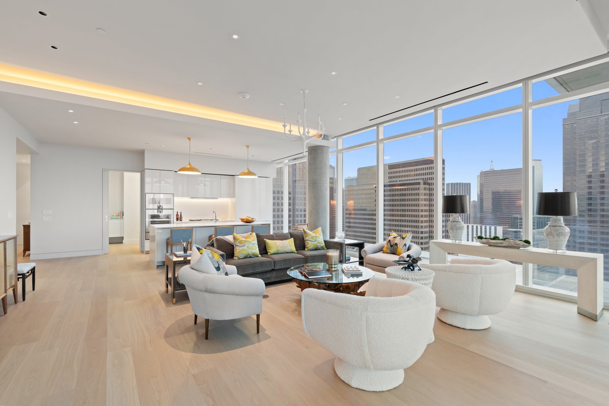 Furnished condo living room with floor-to-ceiling windows overlooking the downtown Dallas skyline.