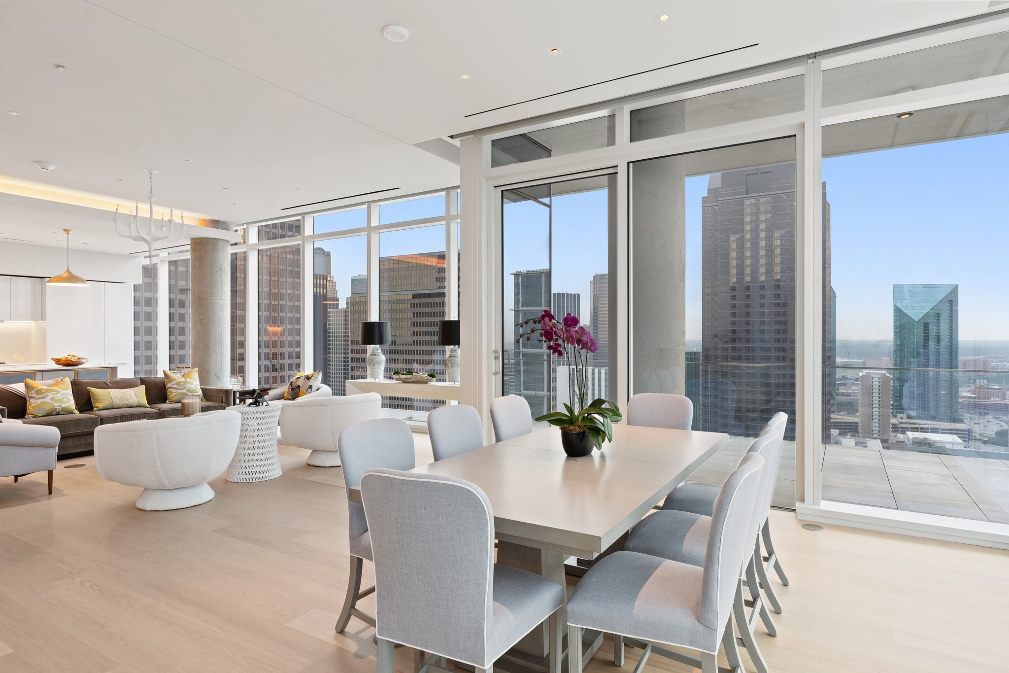 Furnished condo dining area with floor-to-ceiling windows and a Dallas skyline view.