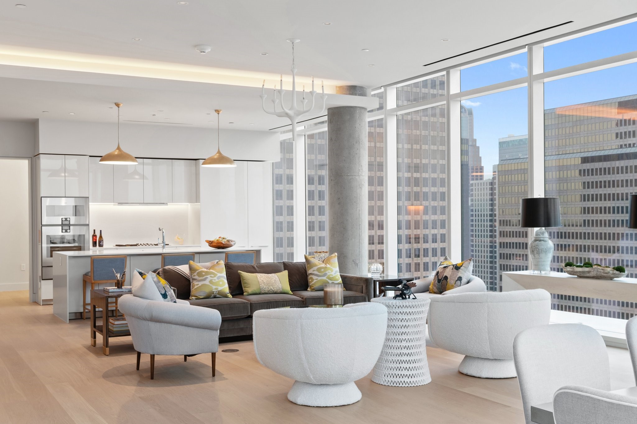 Staged condo living room and kitchen with floor-to-ceiling windows overlooking downtown Dallas towers.