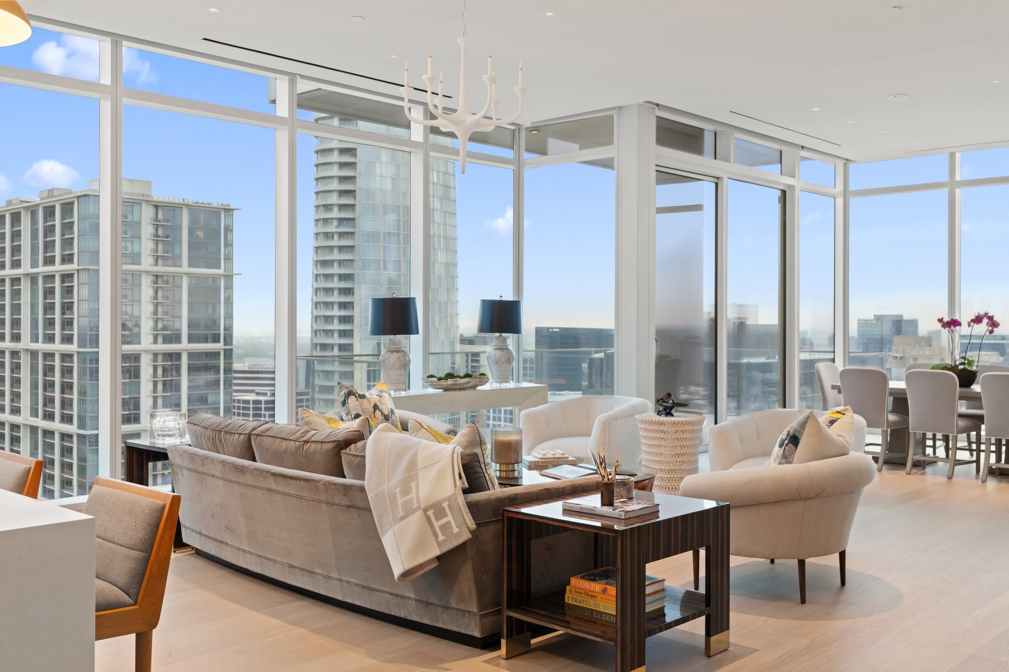Furnished condo living and dining area with floor-to-ceiling windows overlooking downtown Dallas.