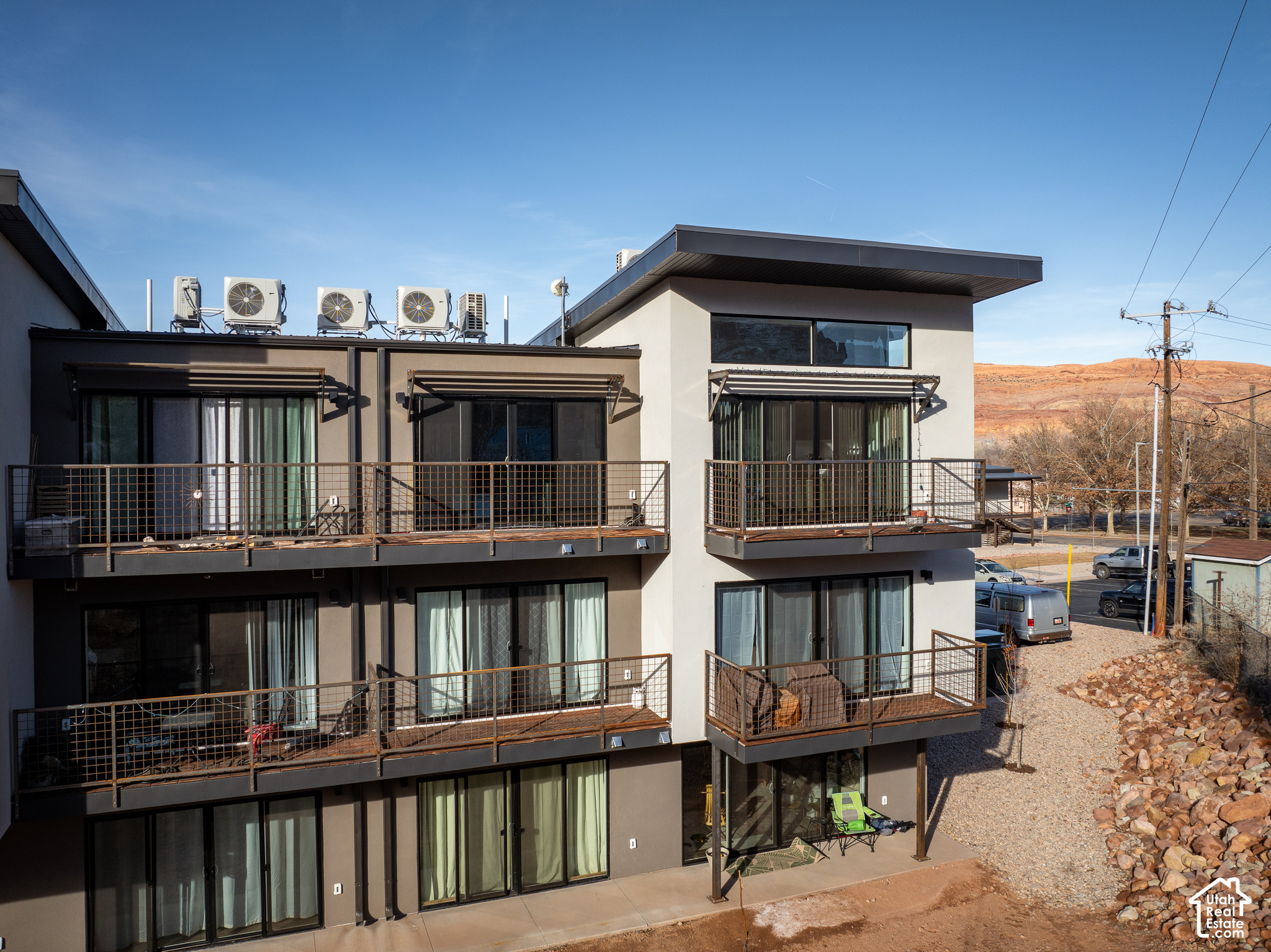 Modern condominium building with metal balconies and red rock hills nearby
