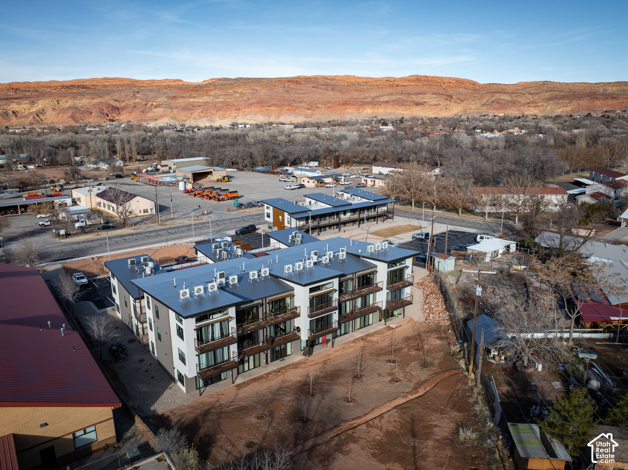 Aerial view of a modern condominium building with balconies, backed by Moab’s red rock mesas.