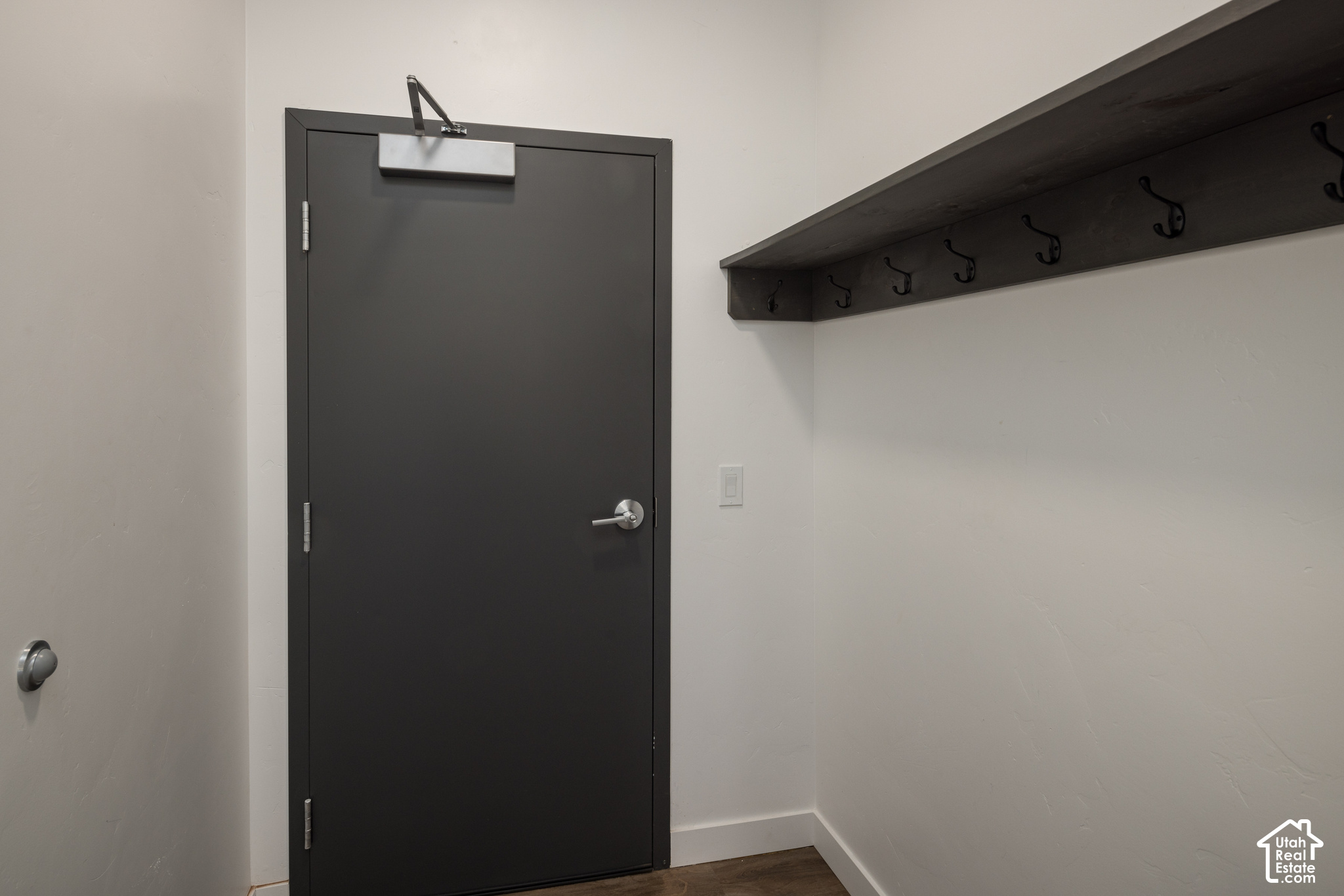 Entryway with a dark gray door and a long wall-mounted coat rack with hooks.
