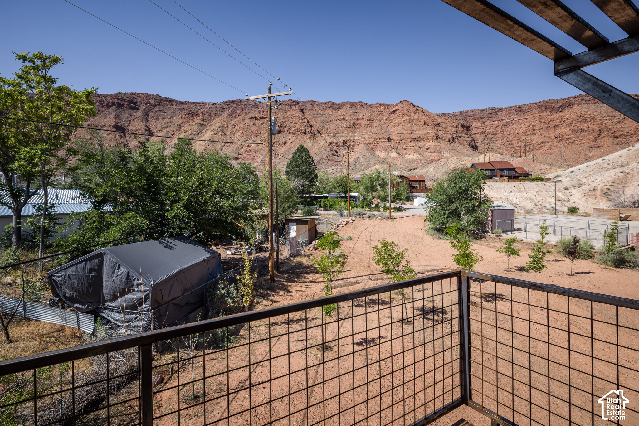 Raised deck overlooks a sandy yard and trees beneath red rock hills.