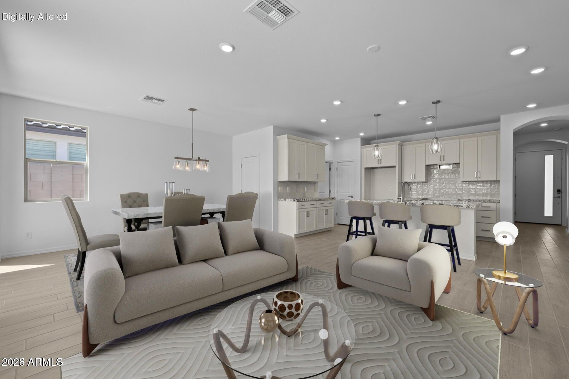 Open-plan living room with neutral sofas facing a kitchen island and dining area.