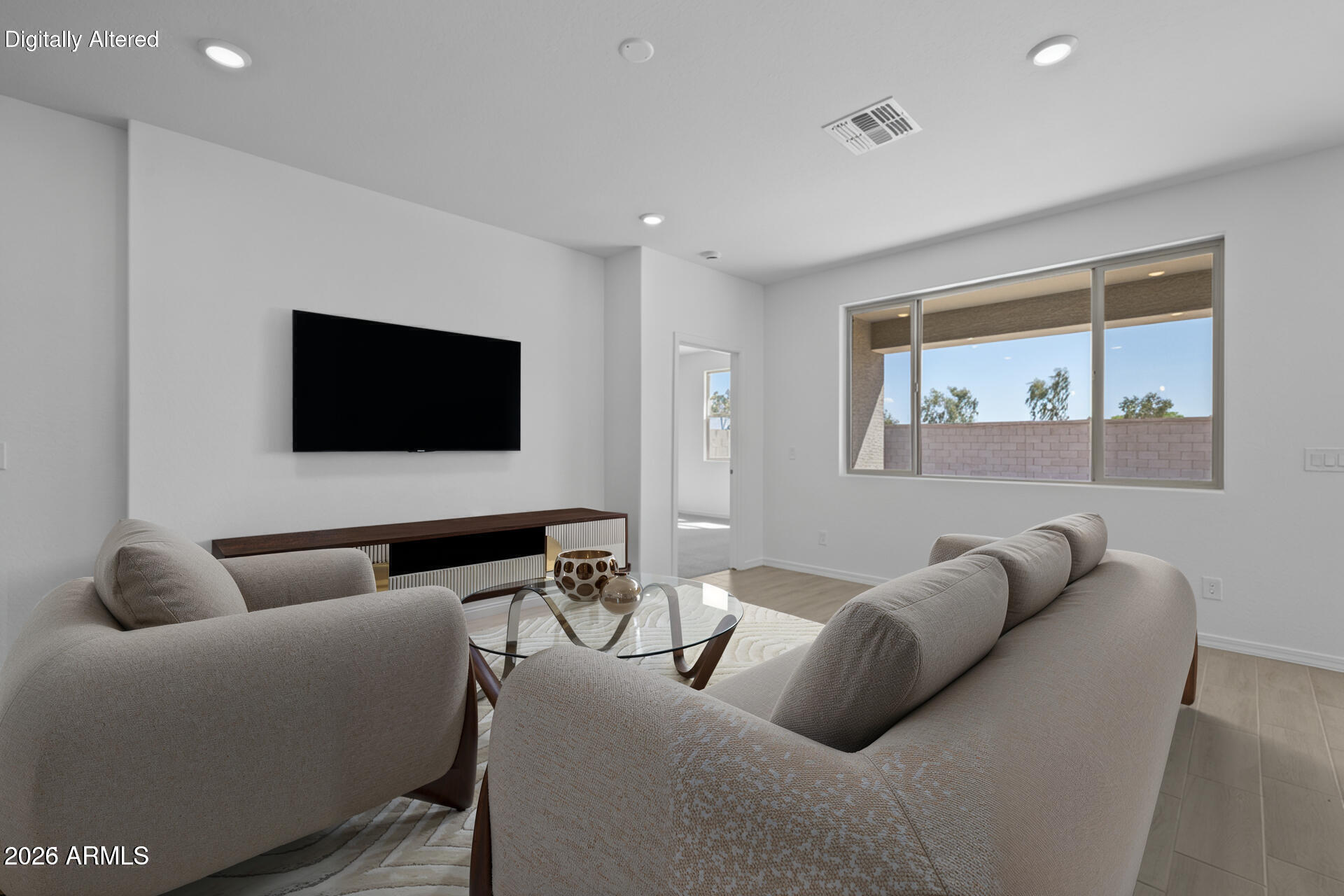 Furnished living room with two sofas, a glass coffee table, wall-mounted TV, and large window.