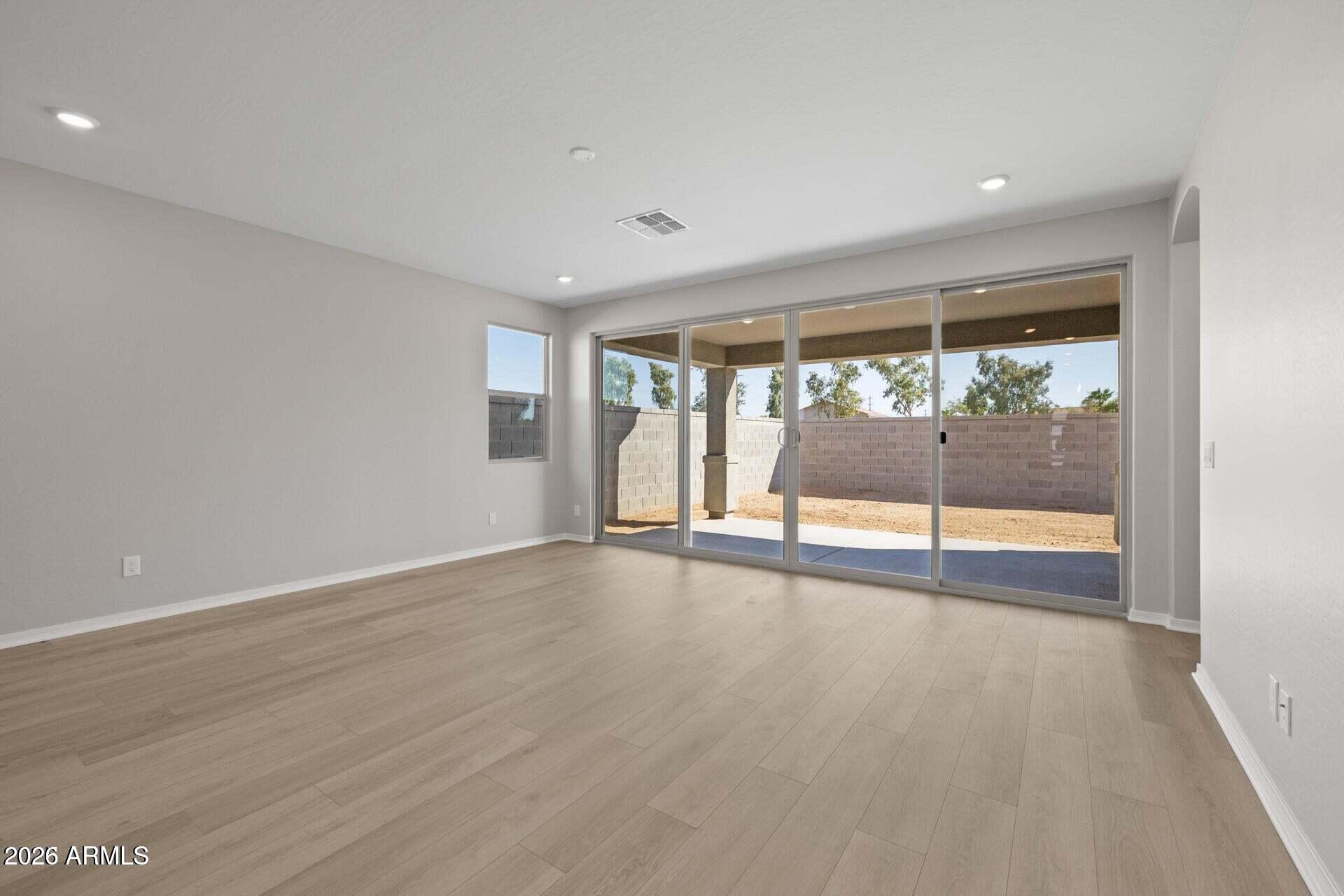 Vacant living room with light wood-look floors and wide sliding glass doors to a covered patio.