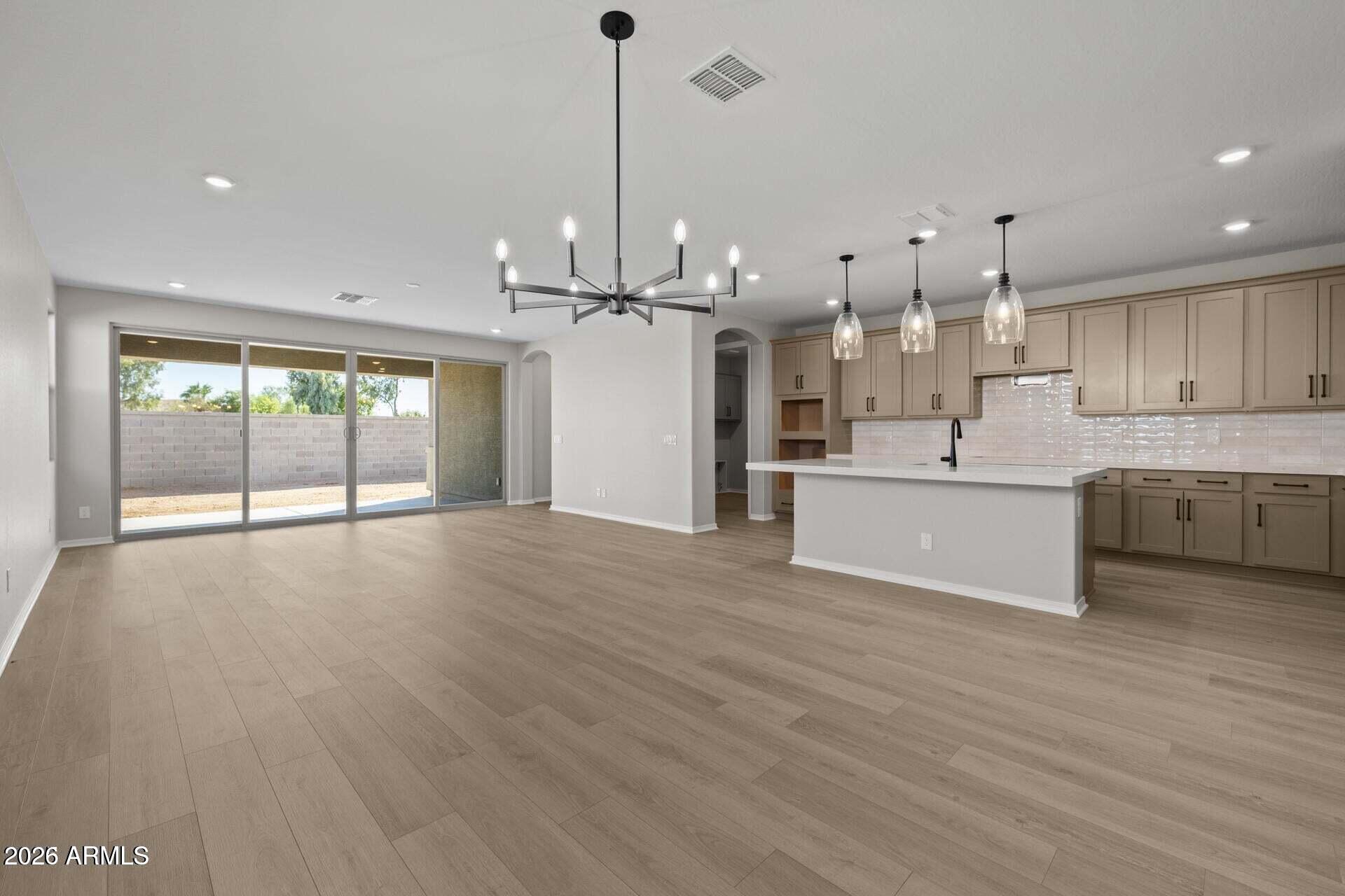 Open kitchen and dining area with a large island, taupe cabinets, and sliding glass doors.