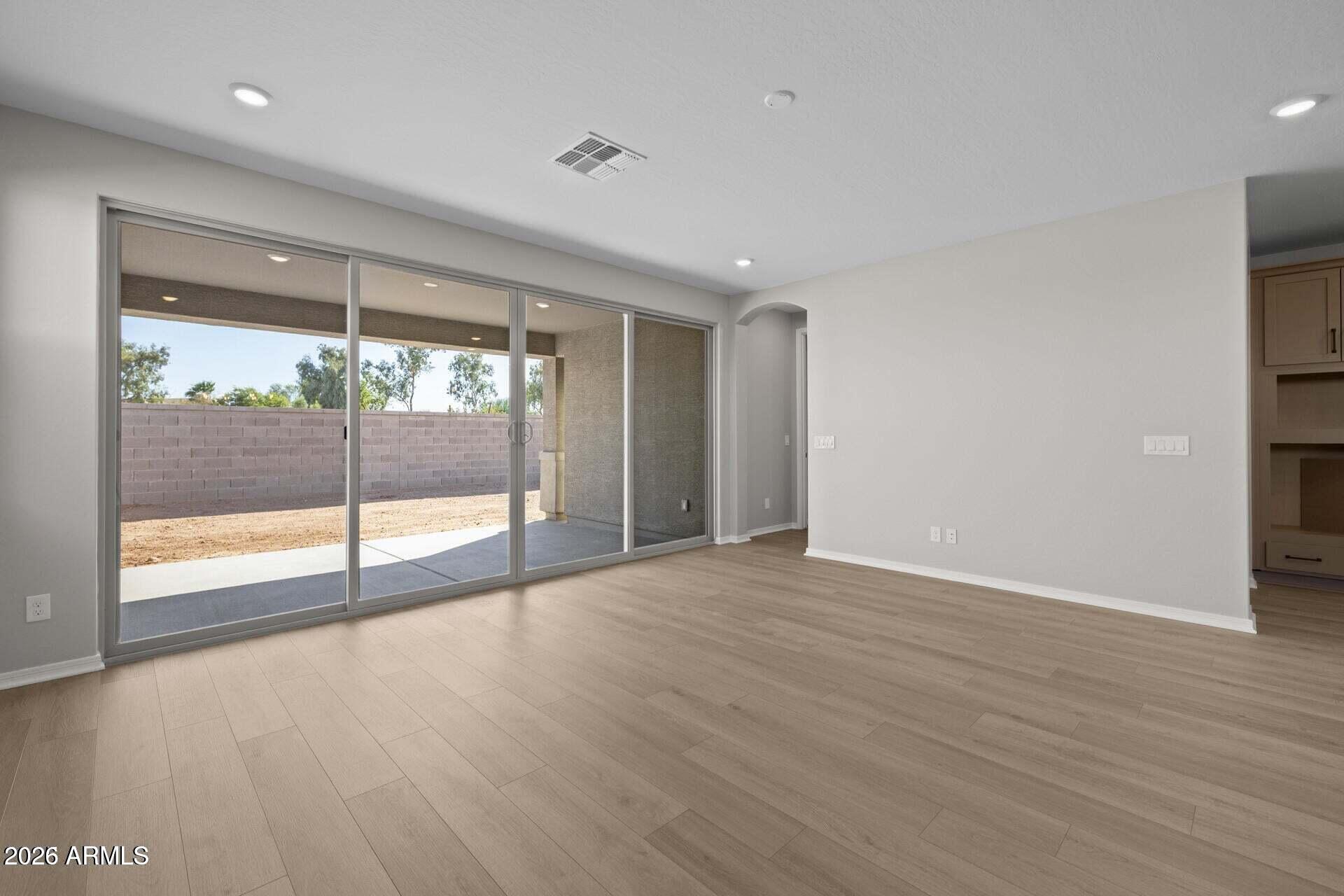 Vacant living room with wood-look tile and wide sliding glass doors to a covered patio.