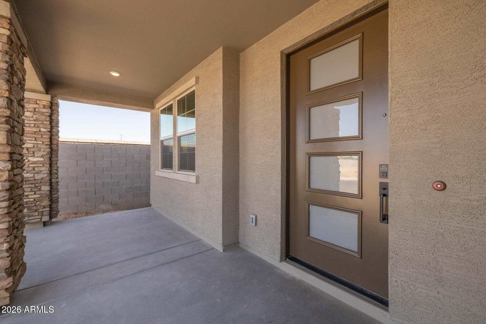 Covered home entry with a brown glass-panel door and stone columns.