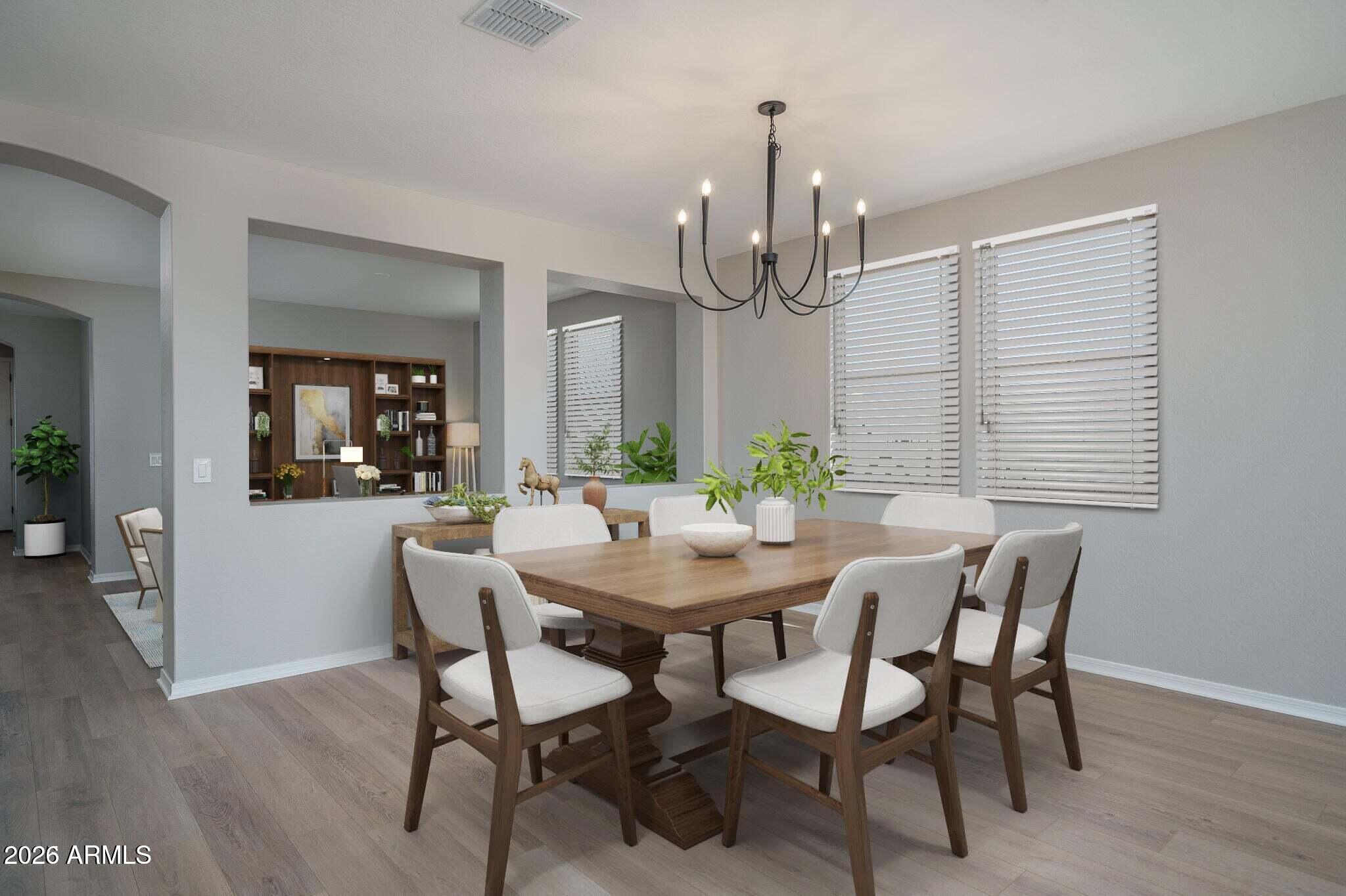 Dining room with a wood table, white chairs, black chandelier, and windows with blinds.
