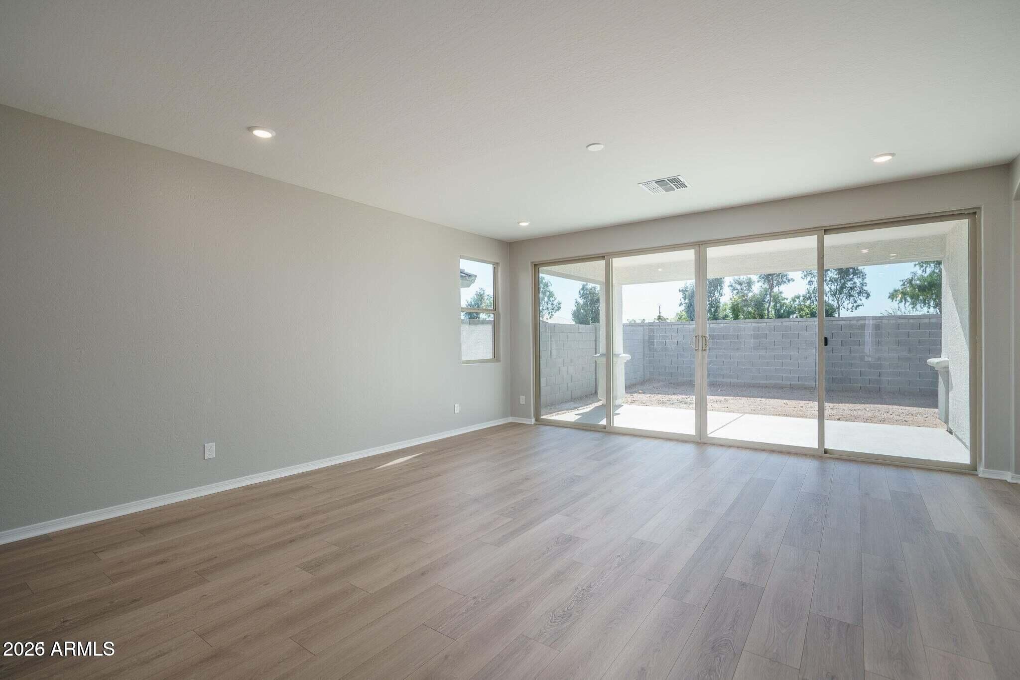 Empty living room with wood-look floors and wide sliding glass doors to a covered patio.