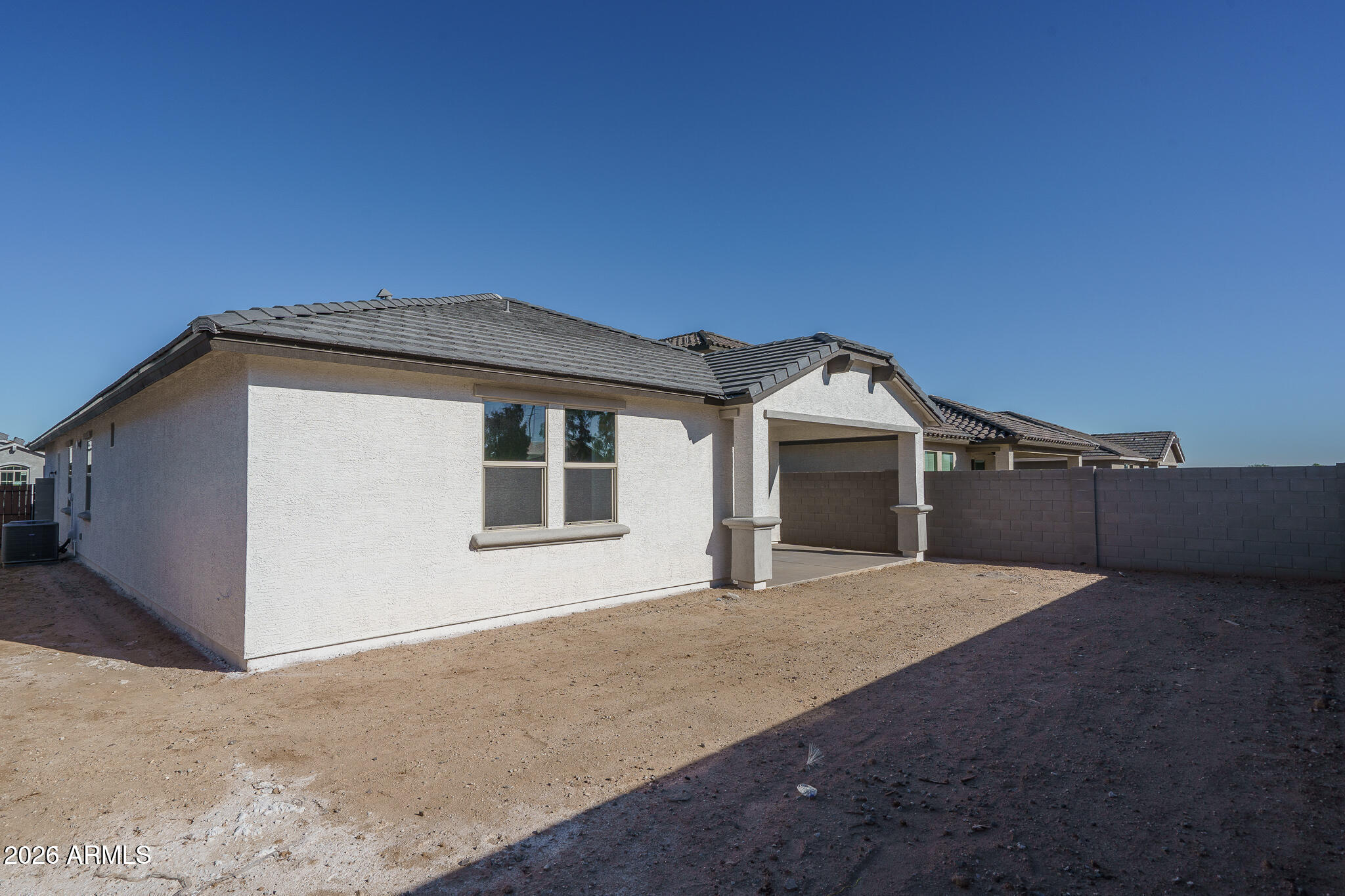 Rear of a single-story home with a covered patio and bare dirt yard.