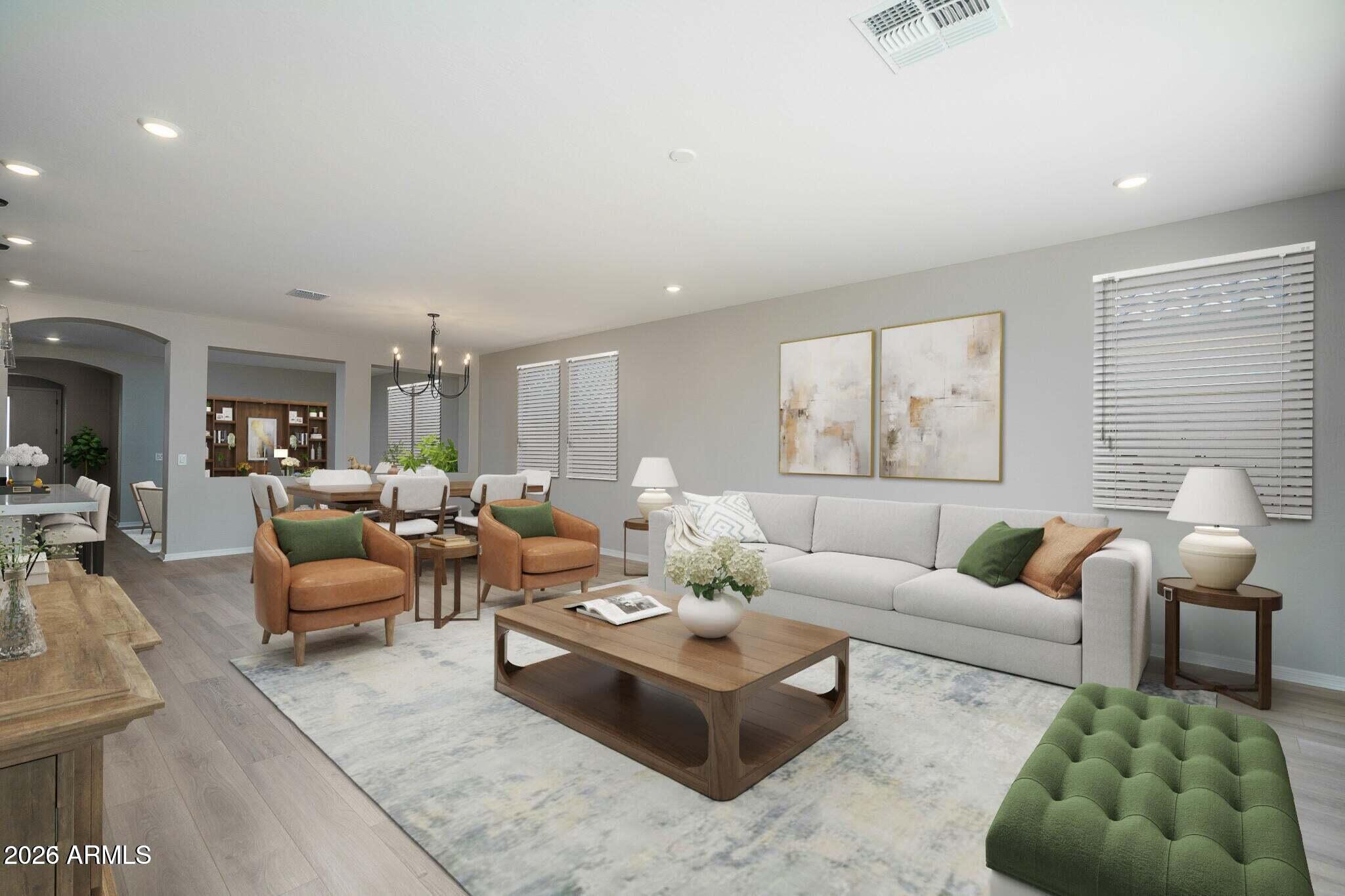 Staged living room with a gray sofa, cognac armchairs, green ottoman, and adjoining dining area.