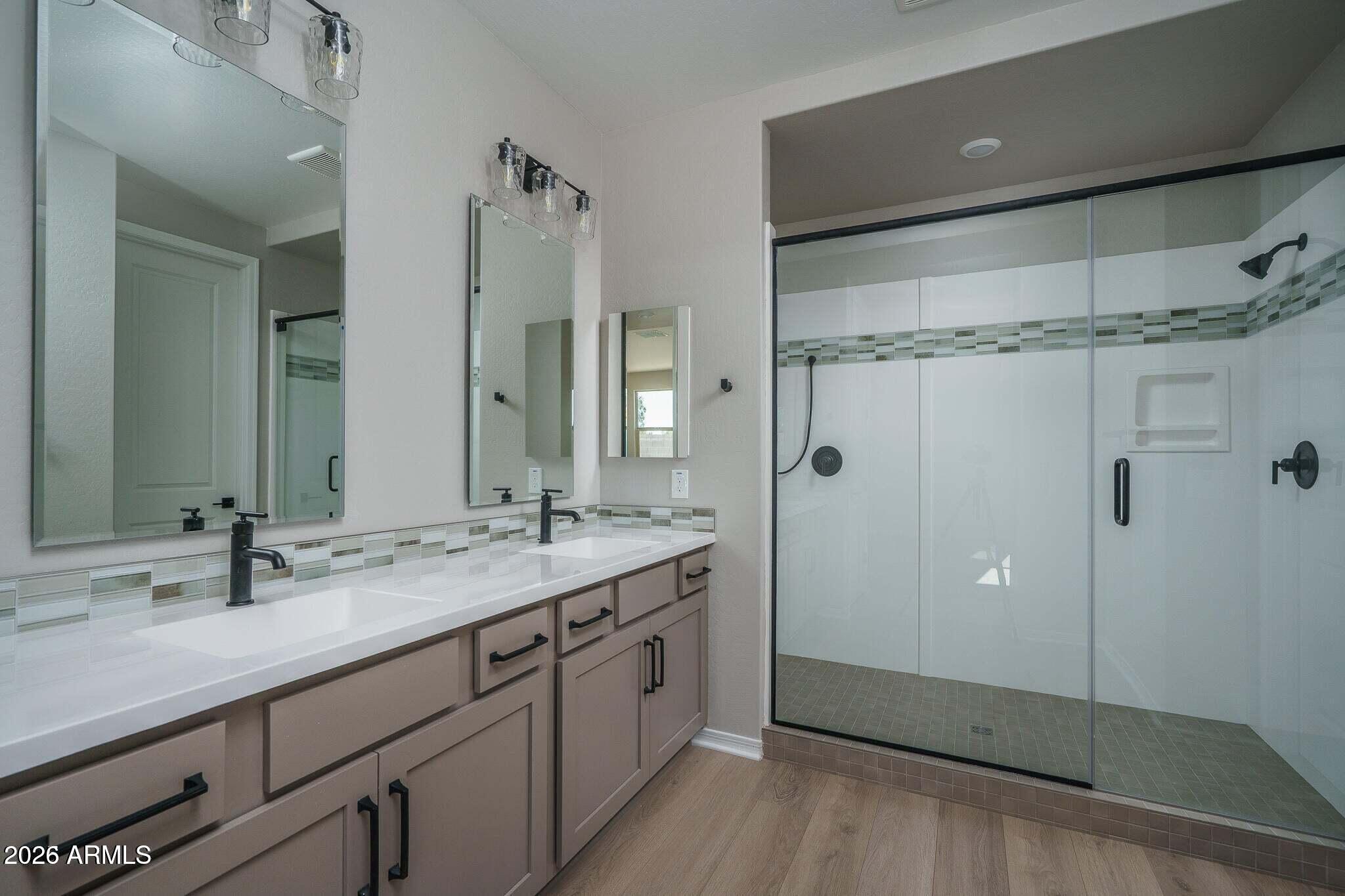 Bathroom with a double-sink vanity and spacious glass-enclosed walk-in shower.