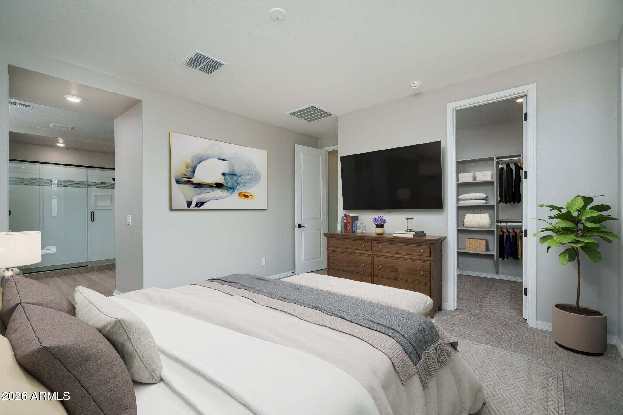Staged bedroom with a large bed, wall-mounted TV, open walk-in closet, and glass shower.