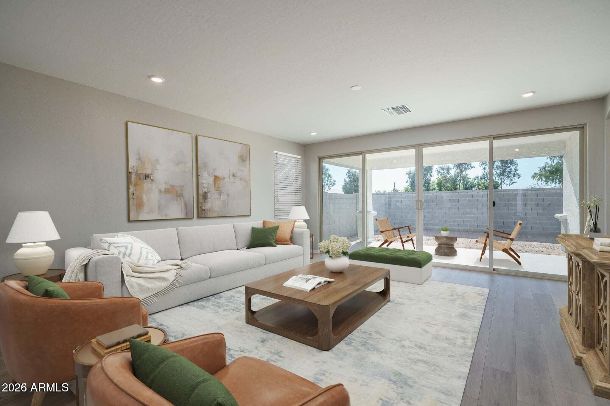 Staged living room with a gray sofa, leather chairs, and sliding glass doors to a walled patio.