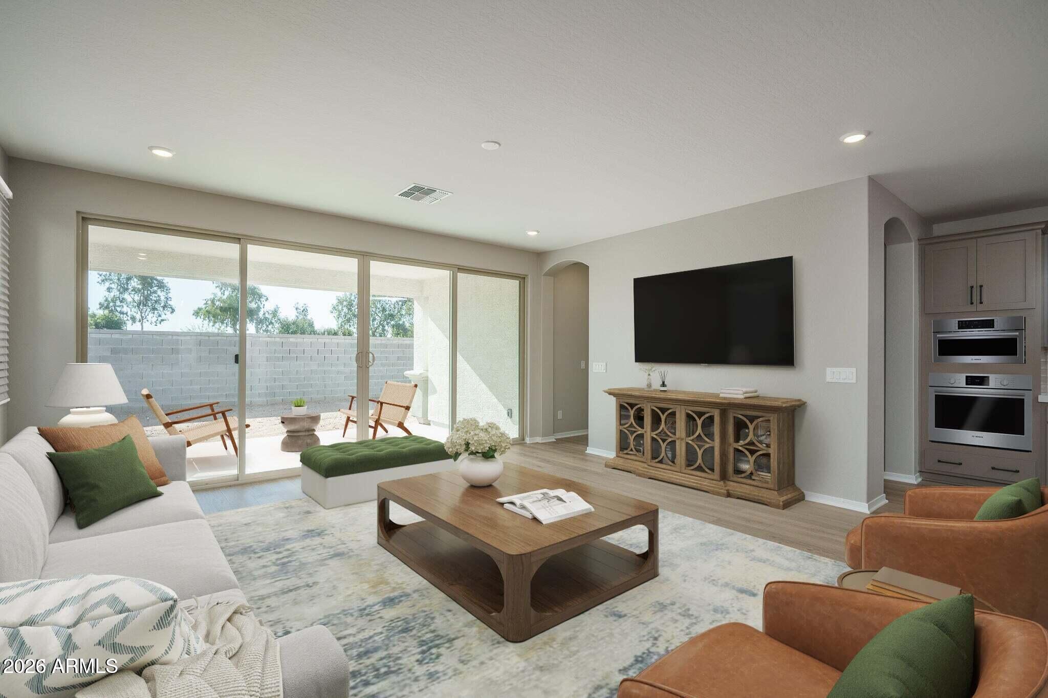 Furnished living room with sliding glass doors to a walled patio and a large wall-mounted TV.