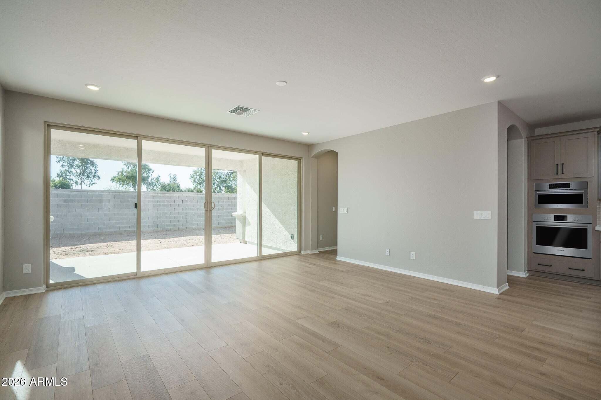 Vacant living area with wide sliding glass doors and built-in double ovens.