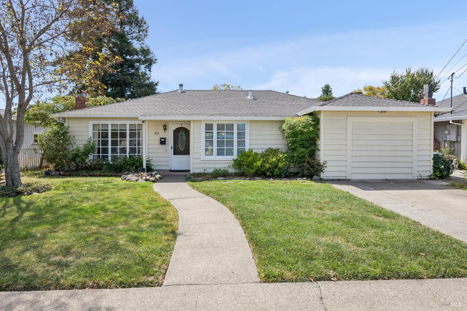 Single-story home with an attached garage, landscaped front lawn, and curved walkway to the entrance.