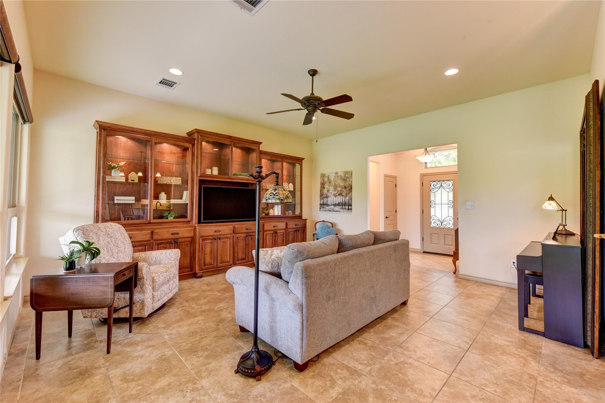 Living room with a built-in wooden entertainment center, gray sofa, and tiled floors.