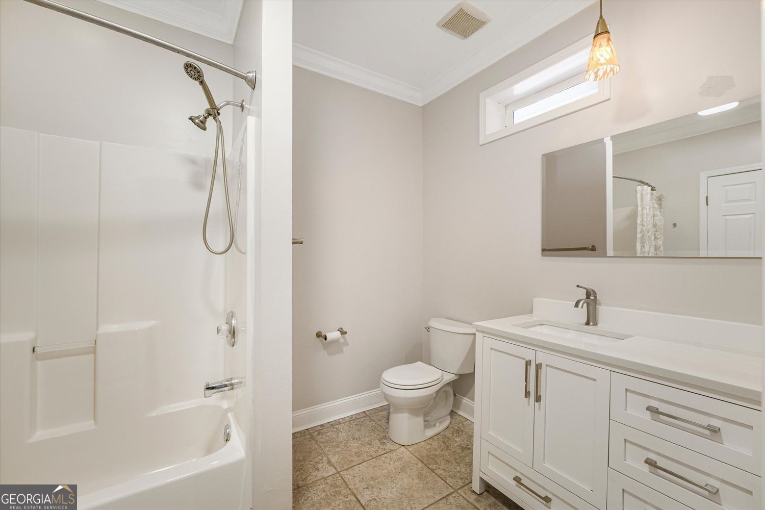 Bathroom with a white tub and shower beside a vanity, toilet, and tiled floor.