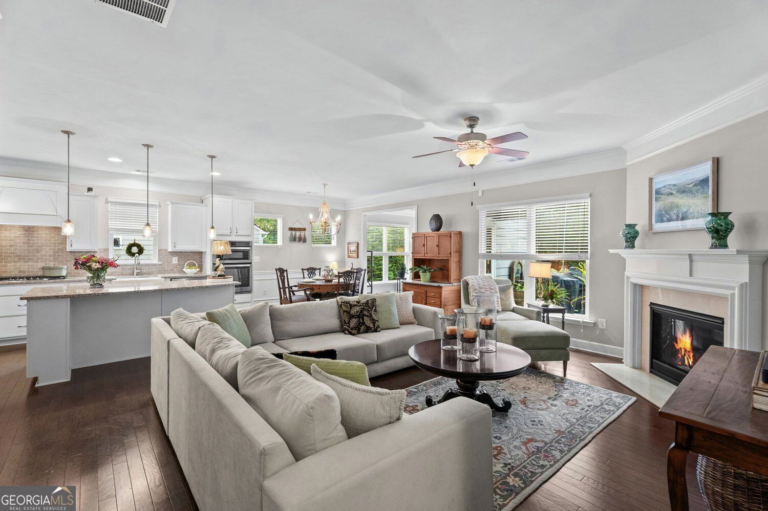 Open-plan living room with fireplace, sectional seating, and kitchen island.