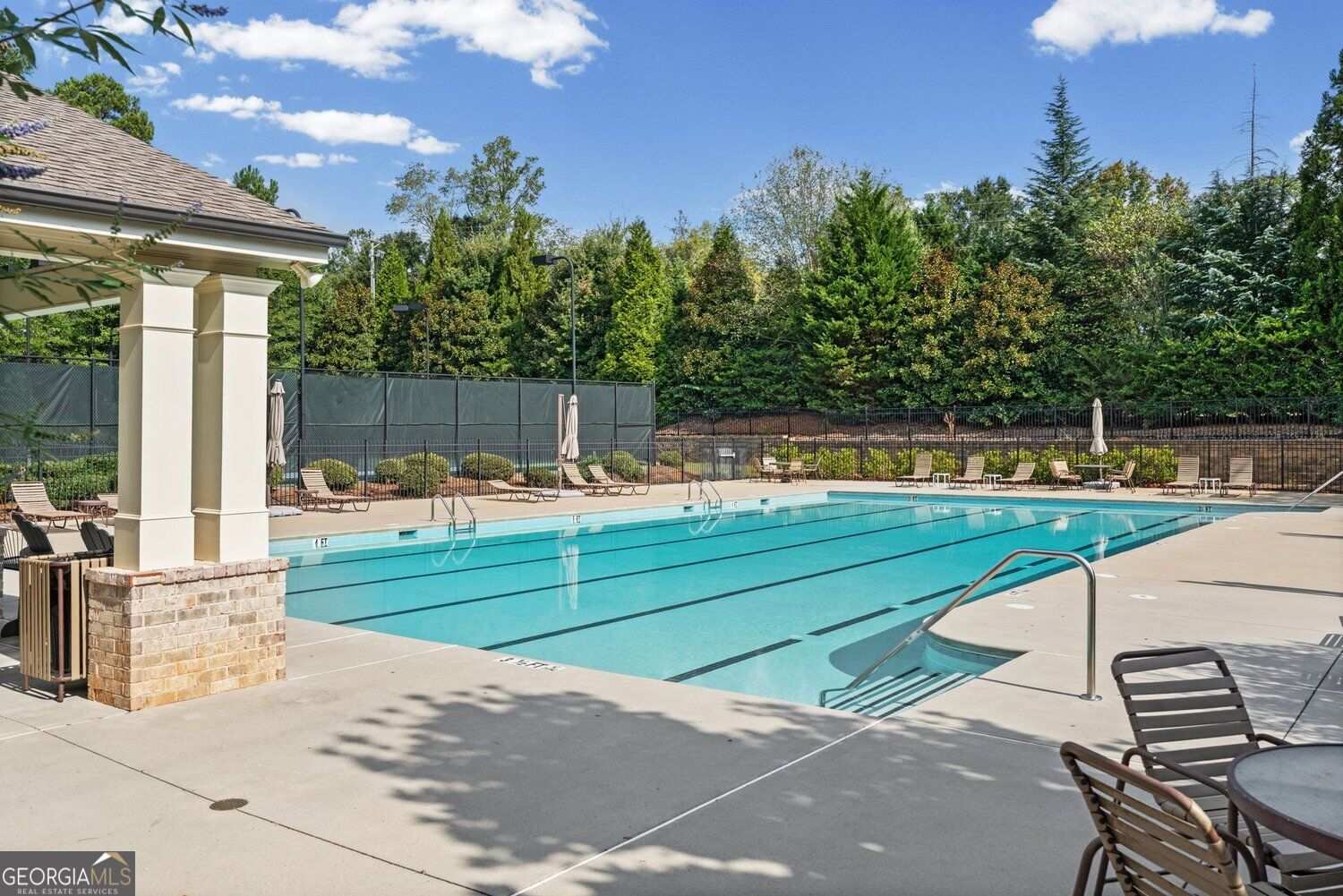 Community swimming pool with lane markings, lounge chairs, and a covered pavilion.
