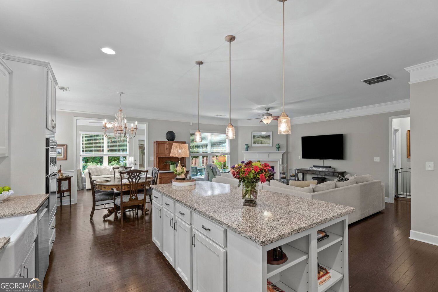 Open-plan kitchen with a large granite island, adjoining dining area, and living room.