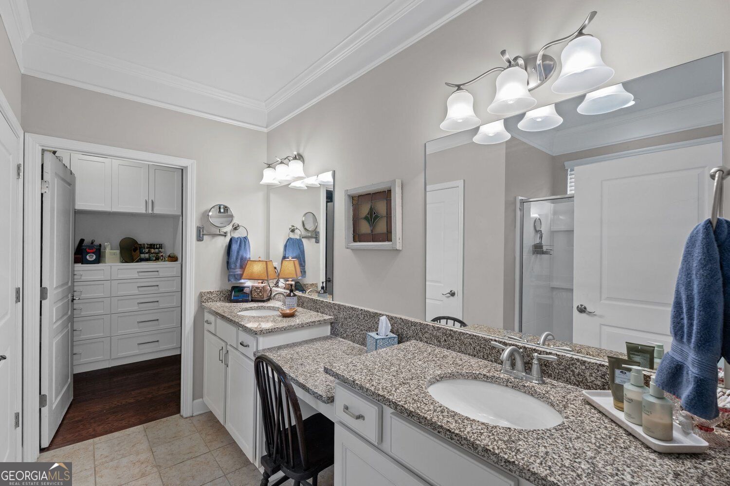 Bathroom with a granite double vanity, large mirrors, and a built-in dressing area.