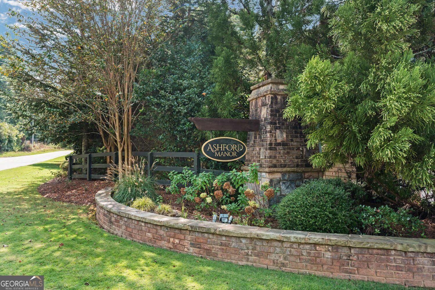 Ashford Manor neighborhood entrance sign beside landscaped brick walls and mature trees.