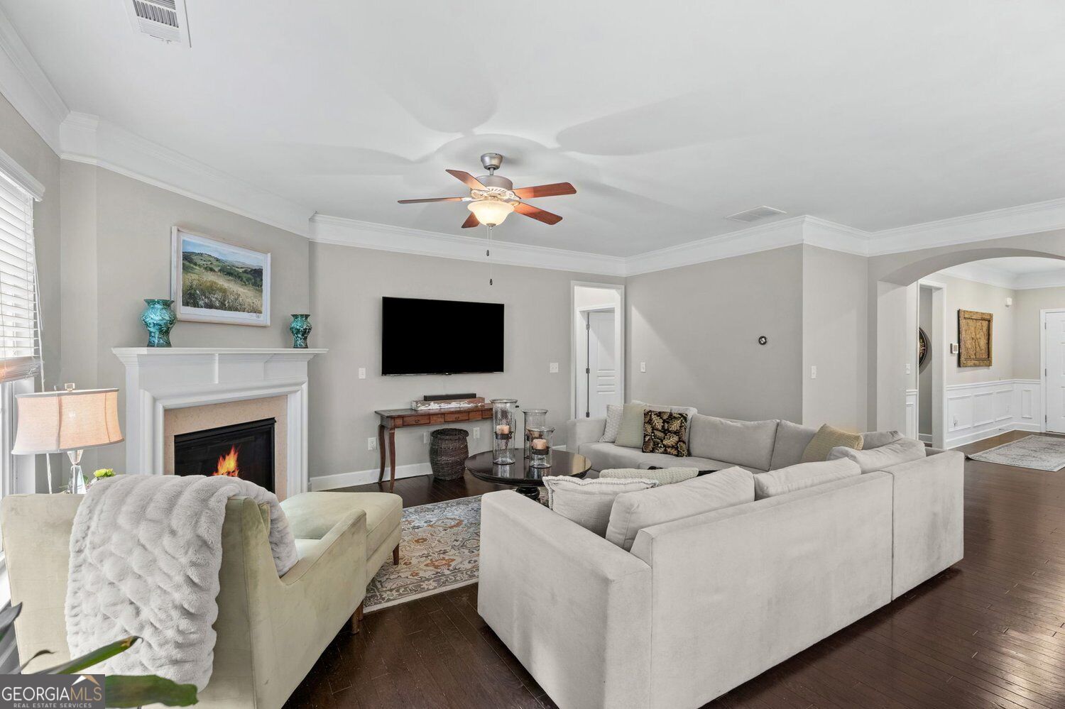 Furnished living room with a white sectional, fireplace, and wall-mounted television.