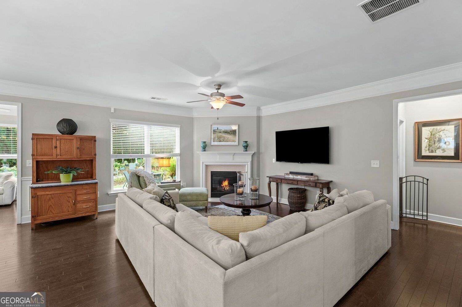 Furnished living room with a sectional sofa, fireplace, wall-mounted TV, and dark hardwood floors.
